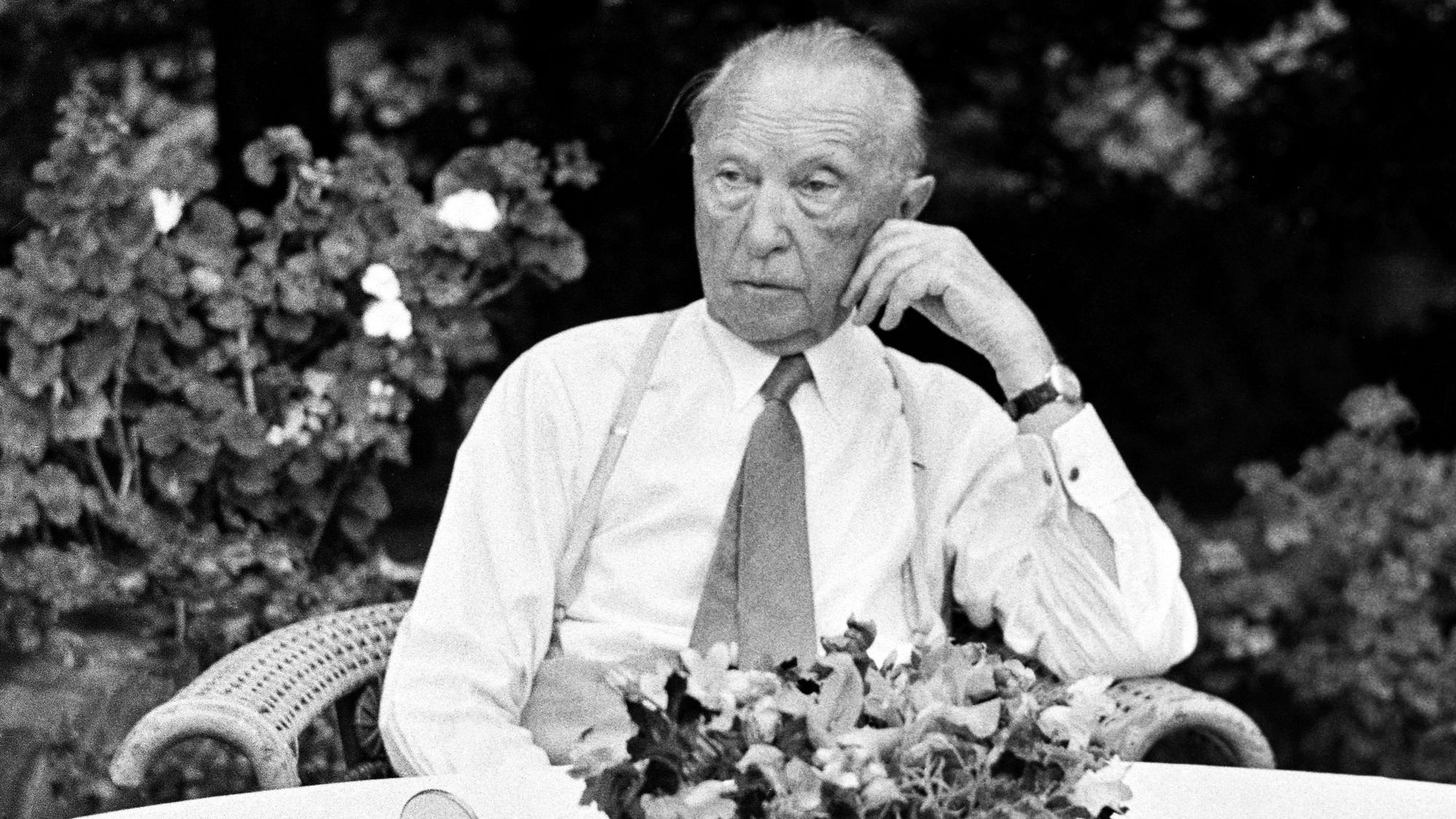 Konrad Adenauer sitzt an einem Tisch.