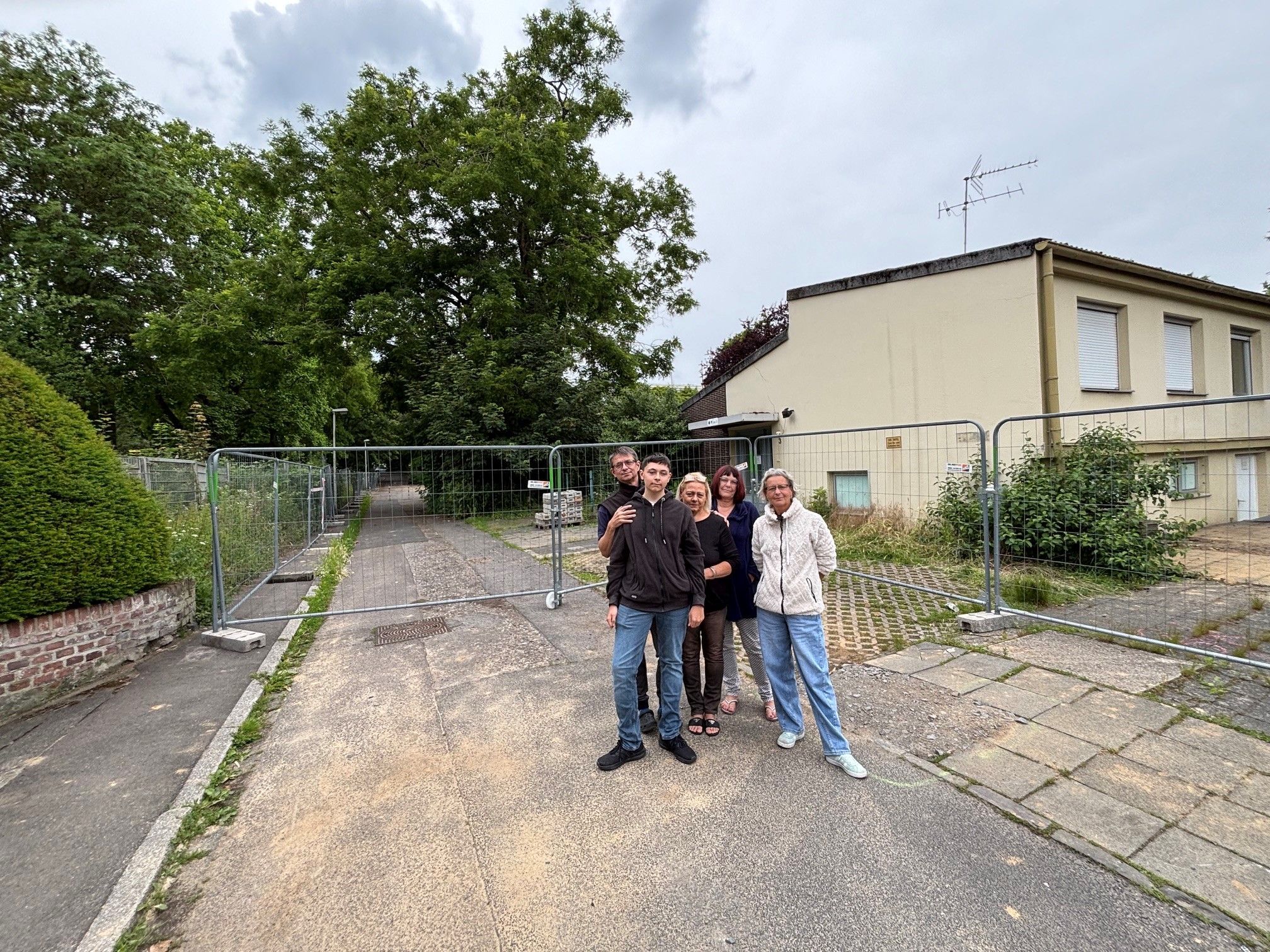 Auf dem Bild ist eine Gruppe von Nachbarn vor einem Bauzaun zu sehen.