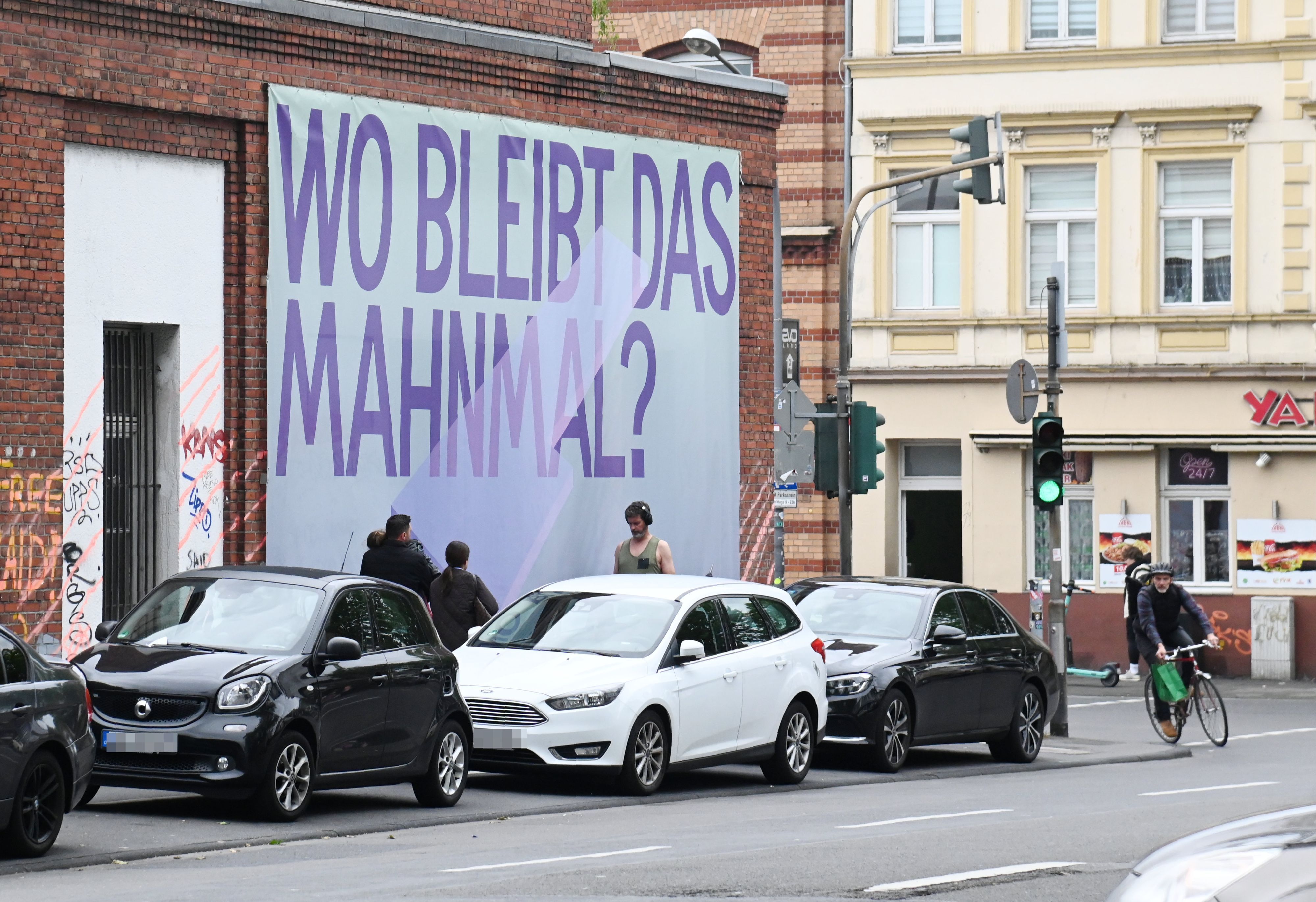 An der Keupstraße hängt ein Transparent „Wo bleibt das Mahnmal?“. Es soll auf das bislang nicht realisierte Denkmal zum Anschlag des NSU in der Keupstraße im Jahr 2004 hinweisen.