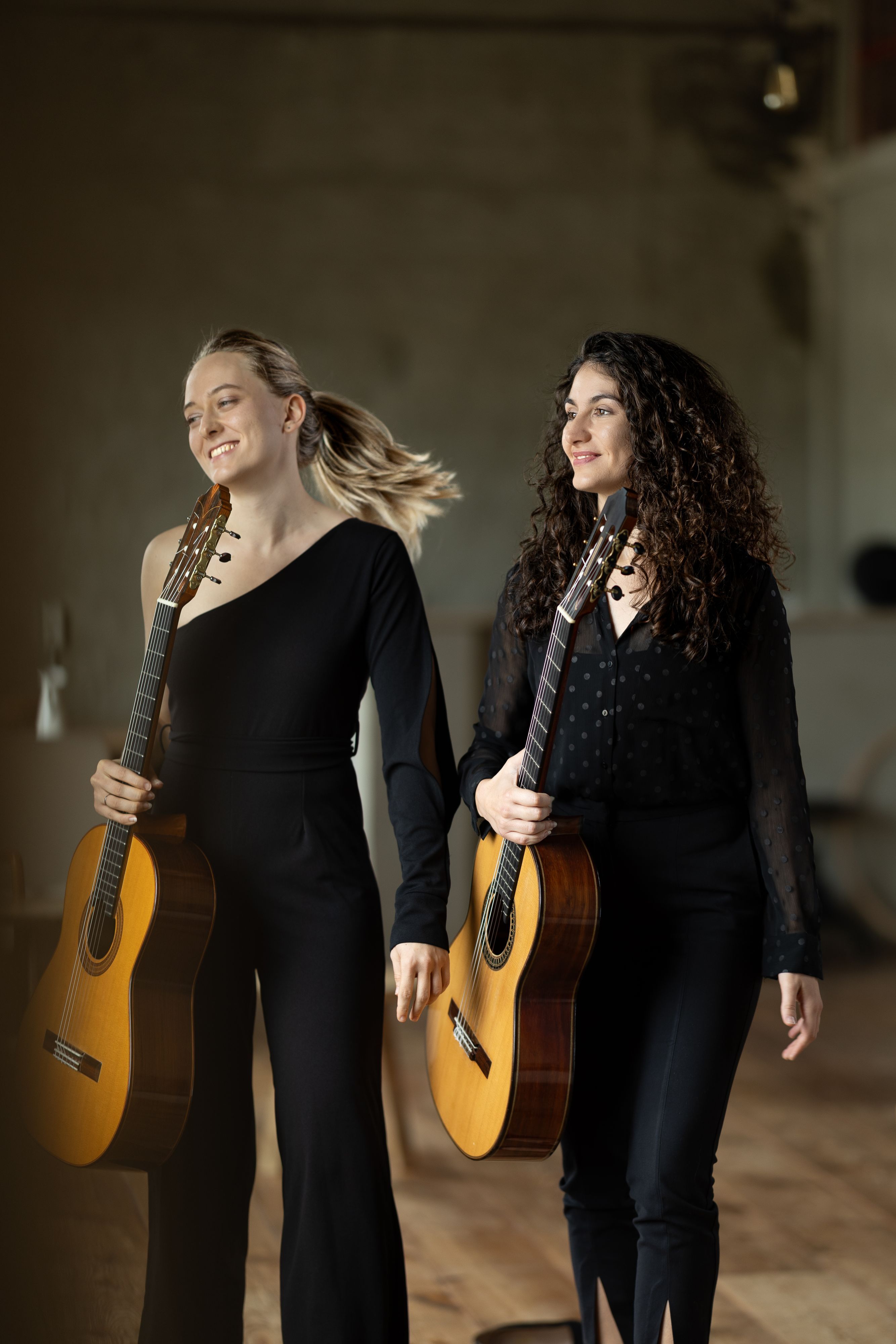 Ana Cižmek (l.) und Petra Stojakovic stehen nebeneinander, halten Gitarren und schauen auf etwas außerhalb des Bildbereichs.