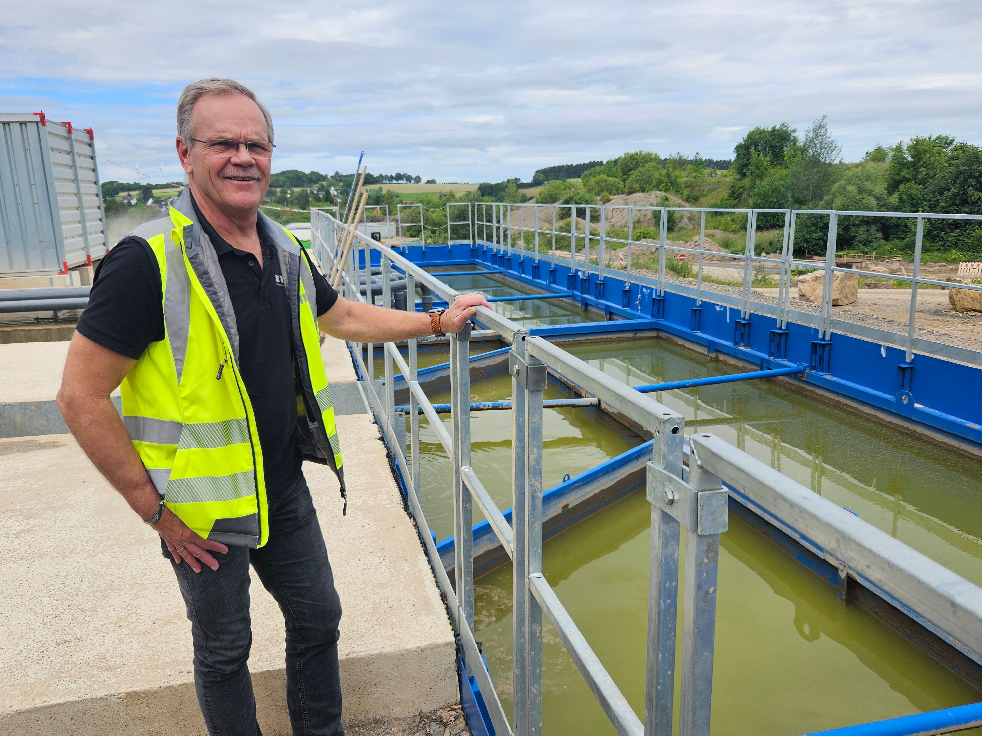 Ein Mann mit gelber Warnweste steht an einem Geländer neben Wasserbecken.