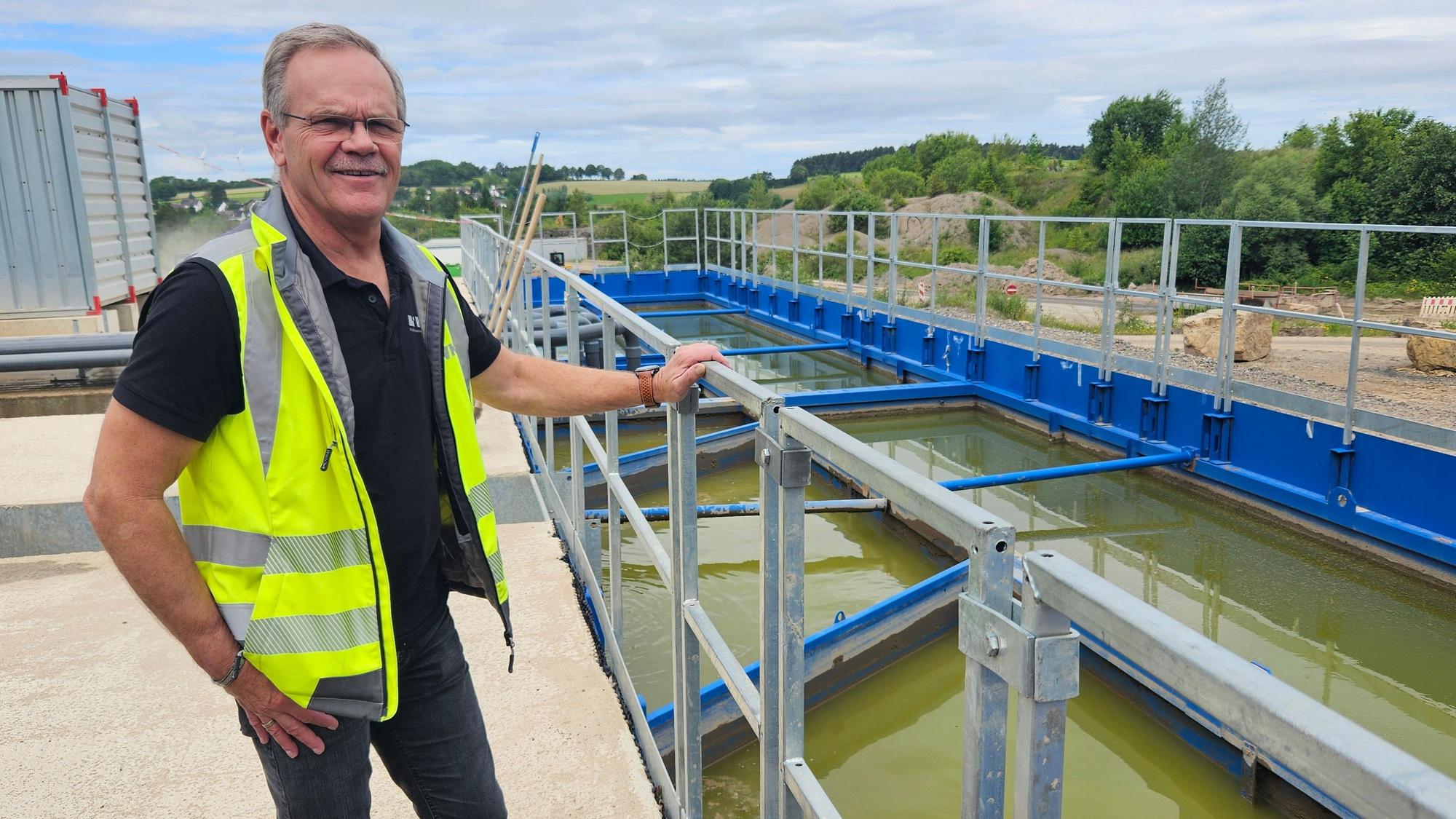 Ein Mann mit gelber Warnweste steht an einem Geländer neben Wasserbecken.