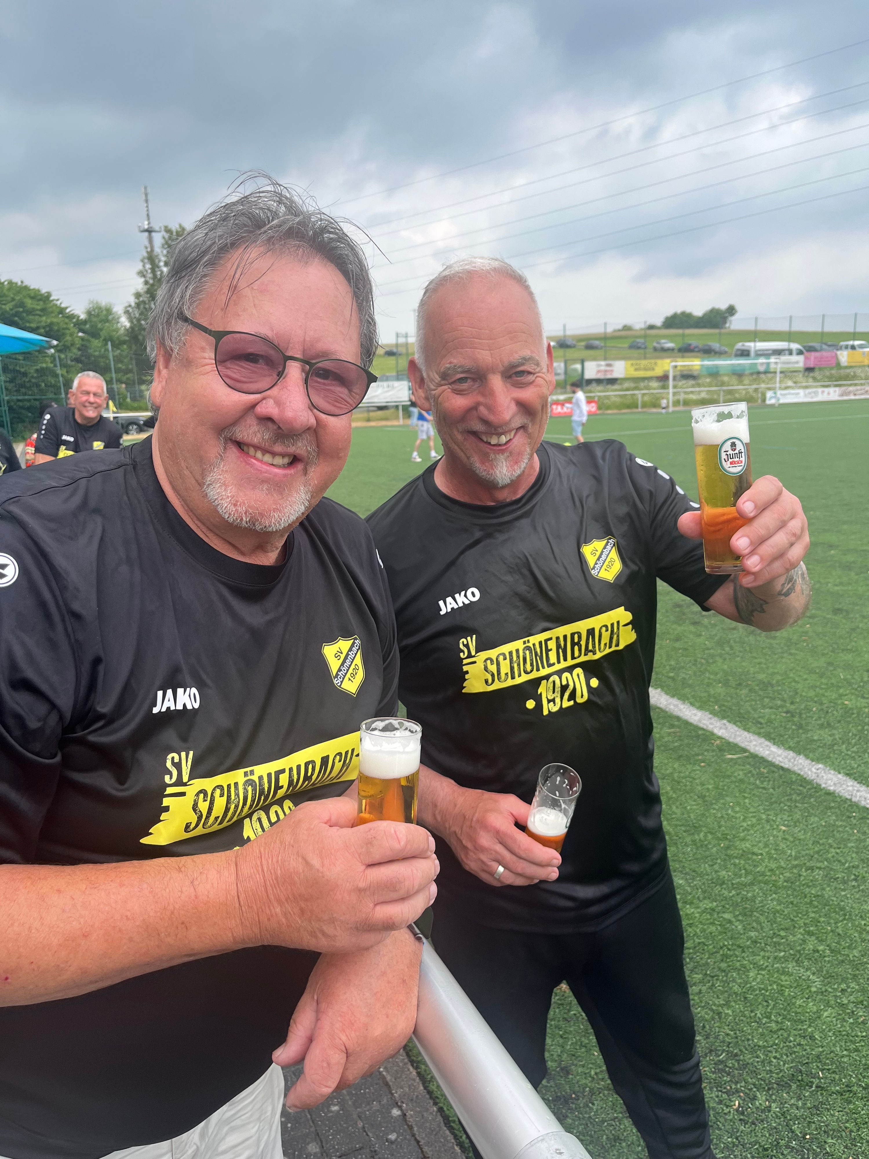 Ein Fußballtrainer und ein Vereinsvorsitzender stoßen miteinander an.