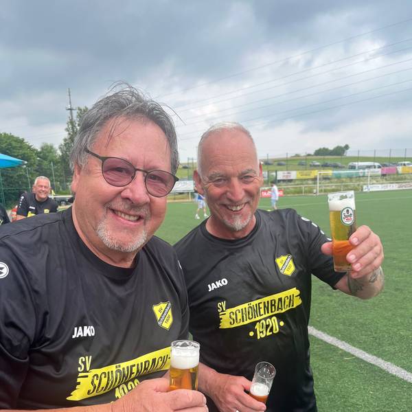 Ein Fußballtrainer und ein Vereinsvorsitzender stoßen miteinander an.