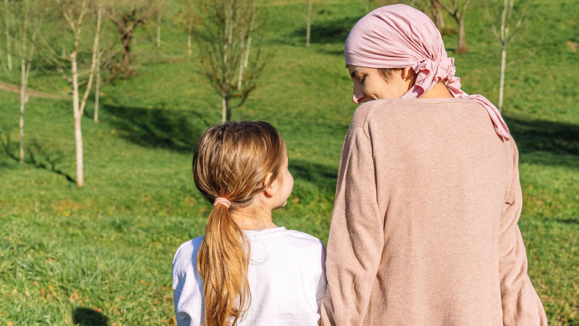 Mutter und Kind sitzen auf einer Wiese, man sieht sie nur von hinten.