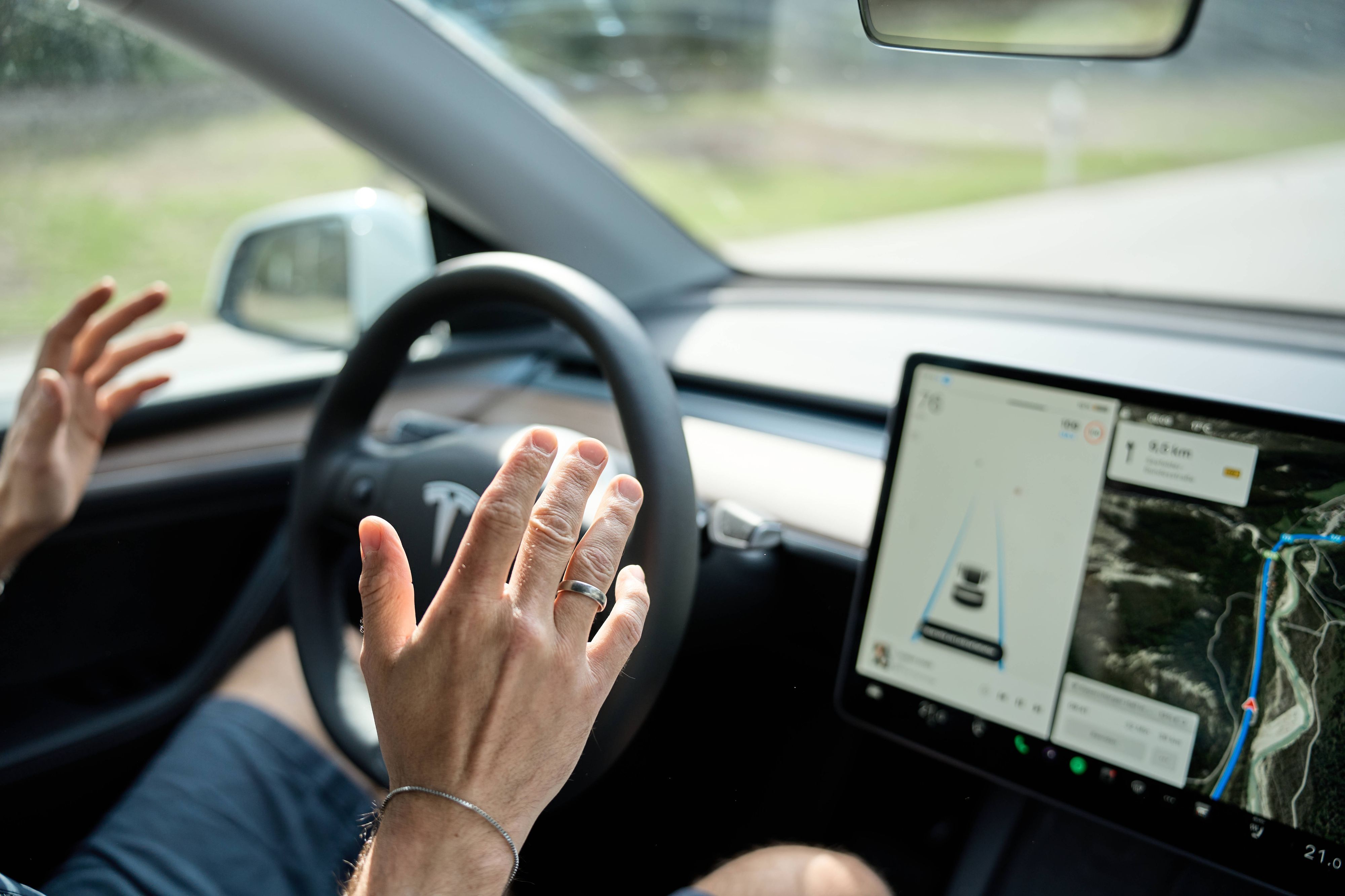 Ein Autofahrer nimmt in einem Tesla die Hände vom Steuer - das Auto lenkt autonom durch den Verkehr.