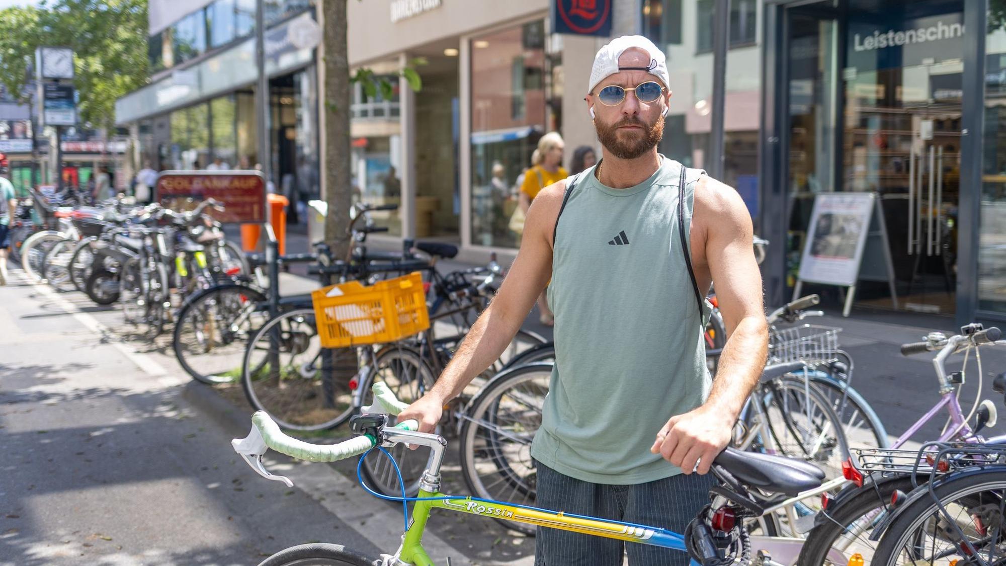 Ein Mann im Tanktop und Sonnebrille schaut ernst in die Kamera.