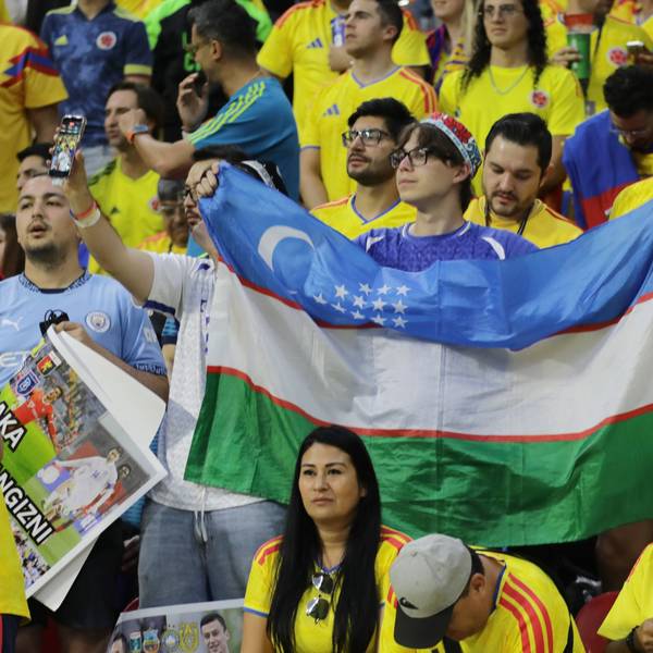 Ein Fan mit Usbekistan-Flagge steht inmitten von kolumbianischen Fans.