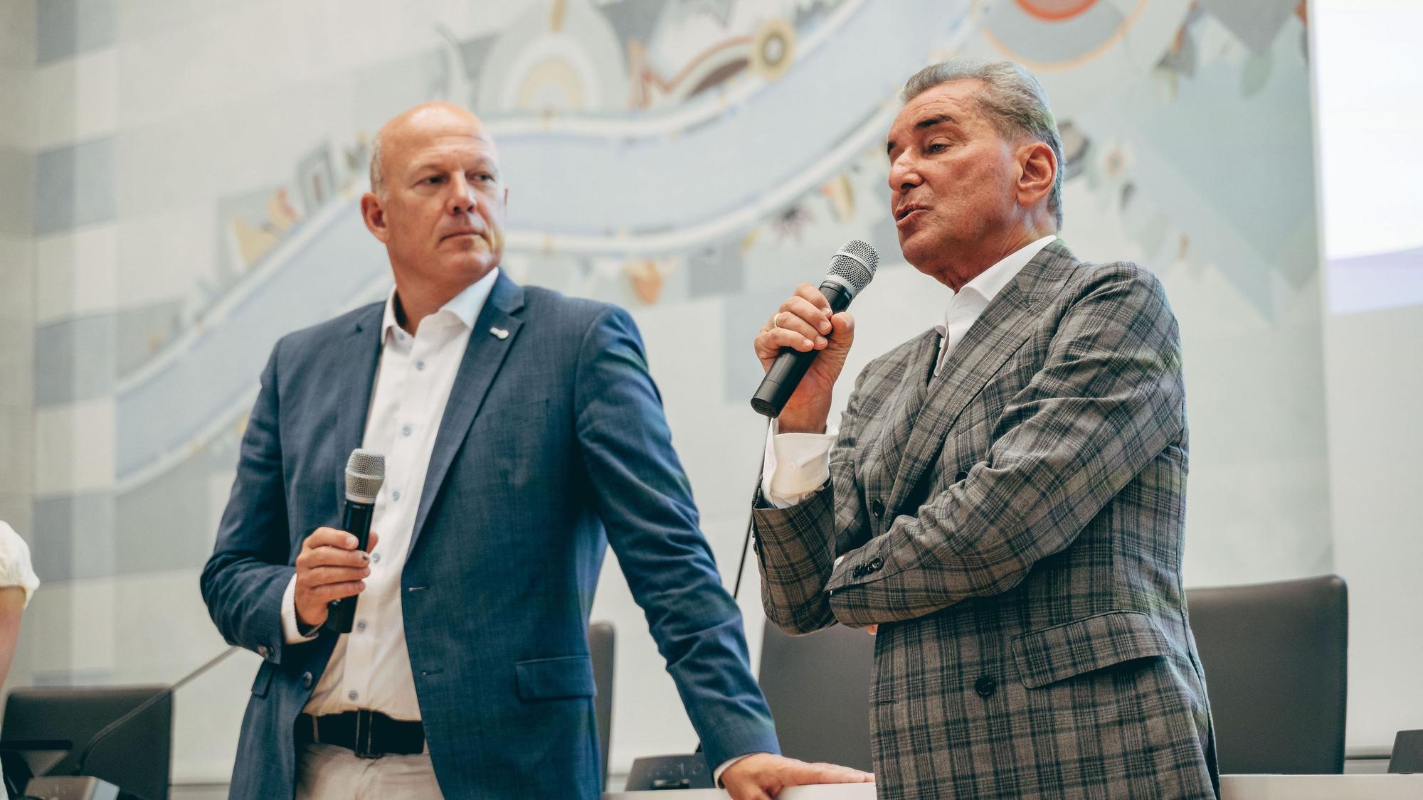Das Bild zeigt Landrat Frank Rock und Michel Friedman. Beide halten Mikrofone. Friedman trägt ein kariertes Sakko.