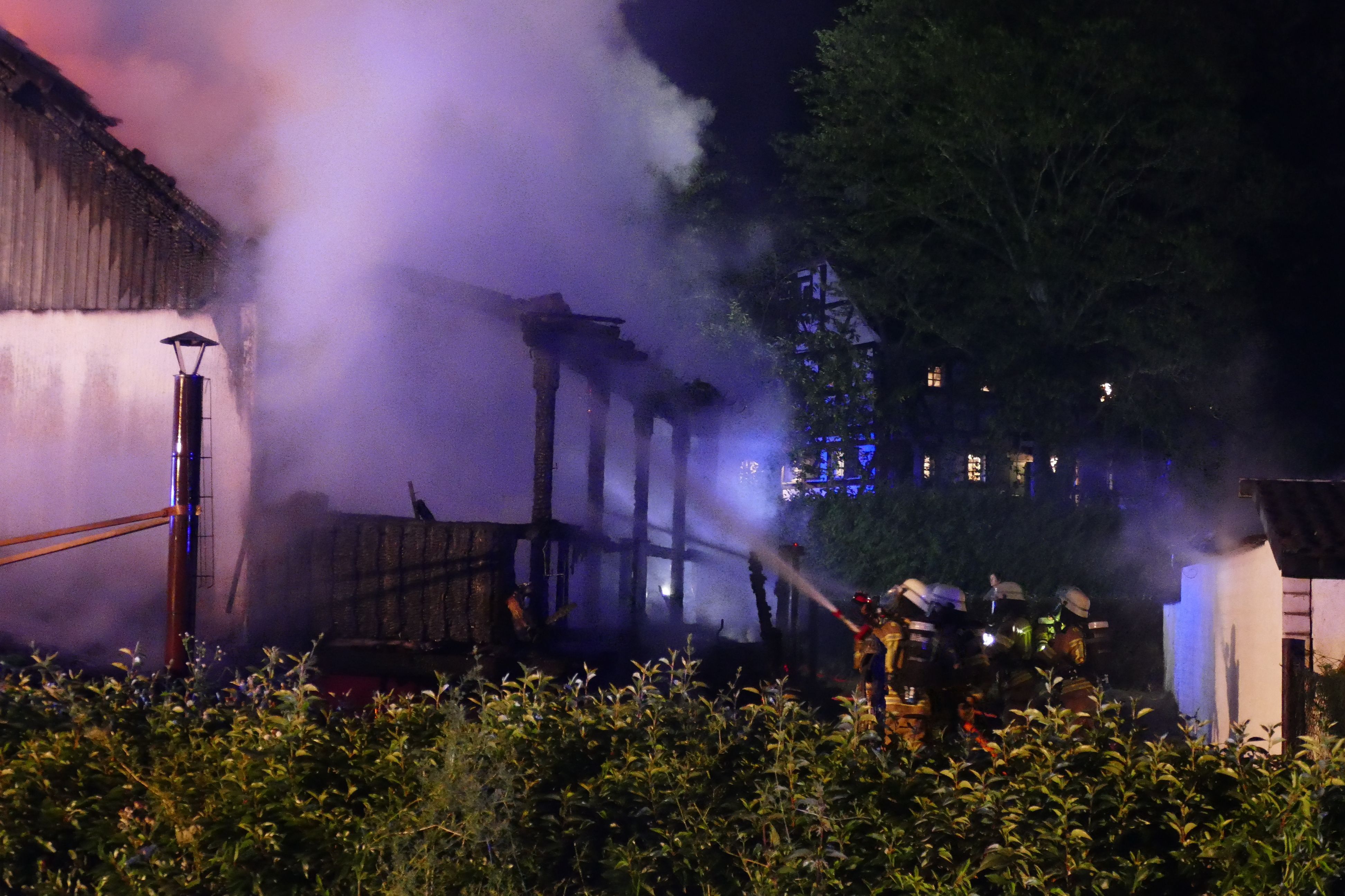 Feuerwehrleute löschen die Terrasse vom Garten aus.