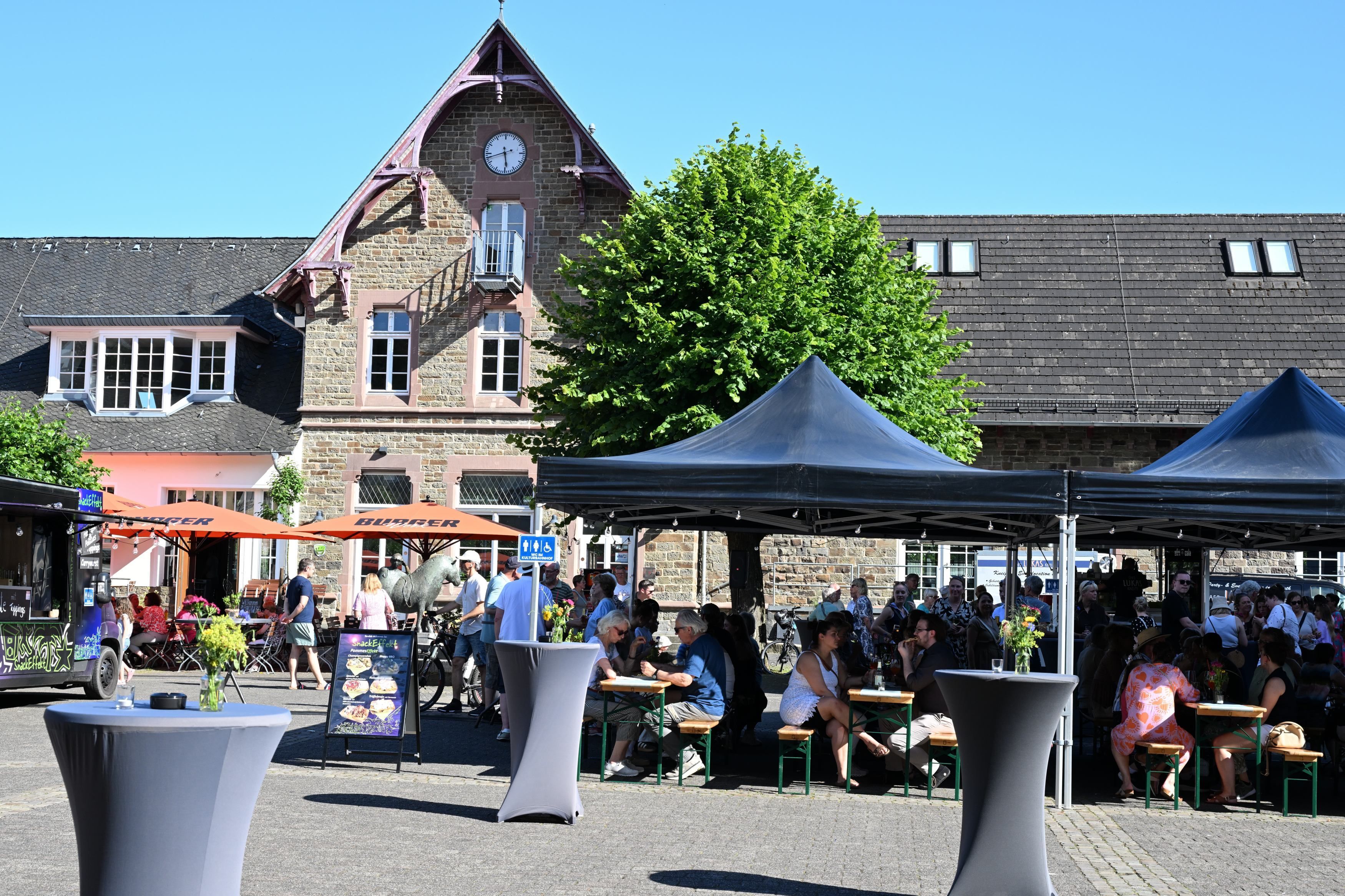 Zu sehen sind einige Pavillons auf einem Platz vor einem alten Gebäude.
