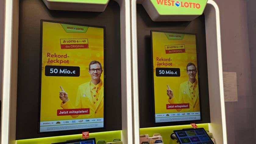 Auf dem Bild sieht man zwei WESTLOTTO-Terminals in einer Lotto-Annahmestelle mit großen Werbedisplays. Auf den Bildschirmen wird ein Rekord-Jackpot von 50 Millionen Euro für LOTTO 6aus49 beworben.