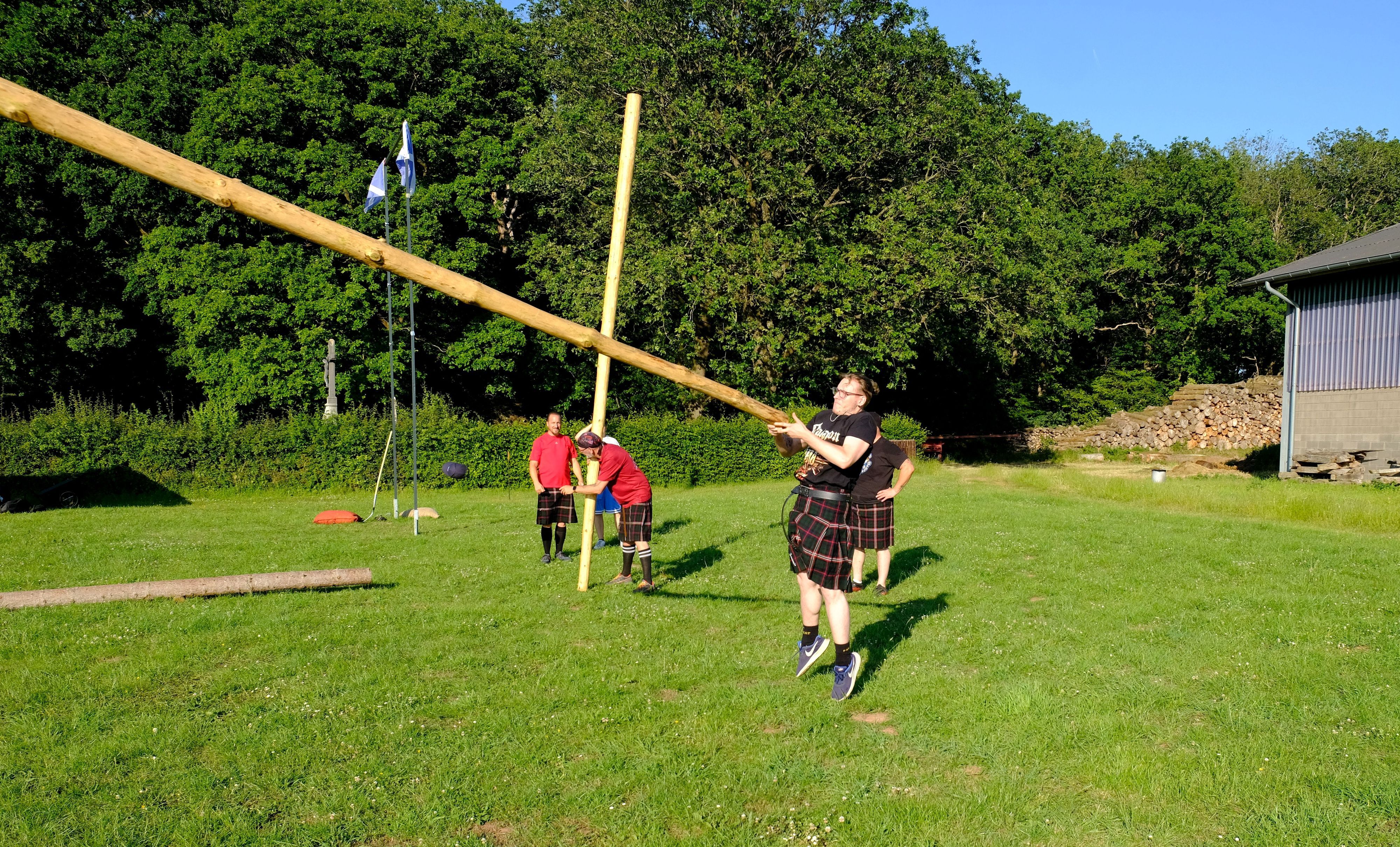 Ein Athlet der Hunting Tartans im Kilt beim Baumstammwerfen auf dem Bolzplatz in Hostel.
