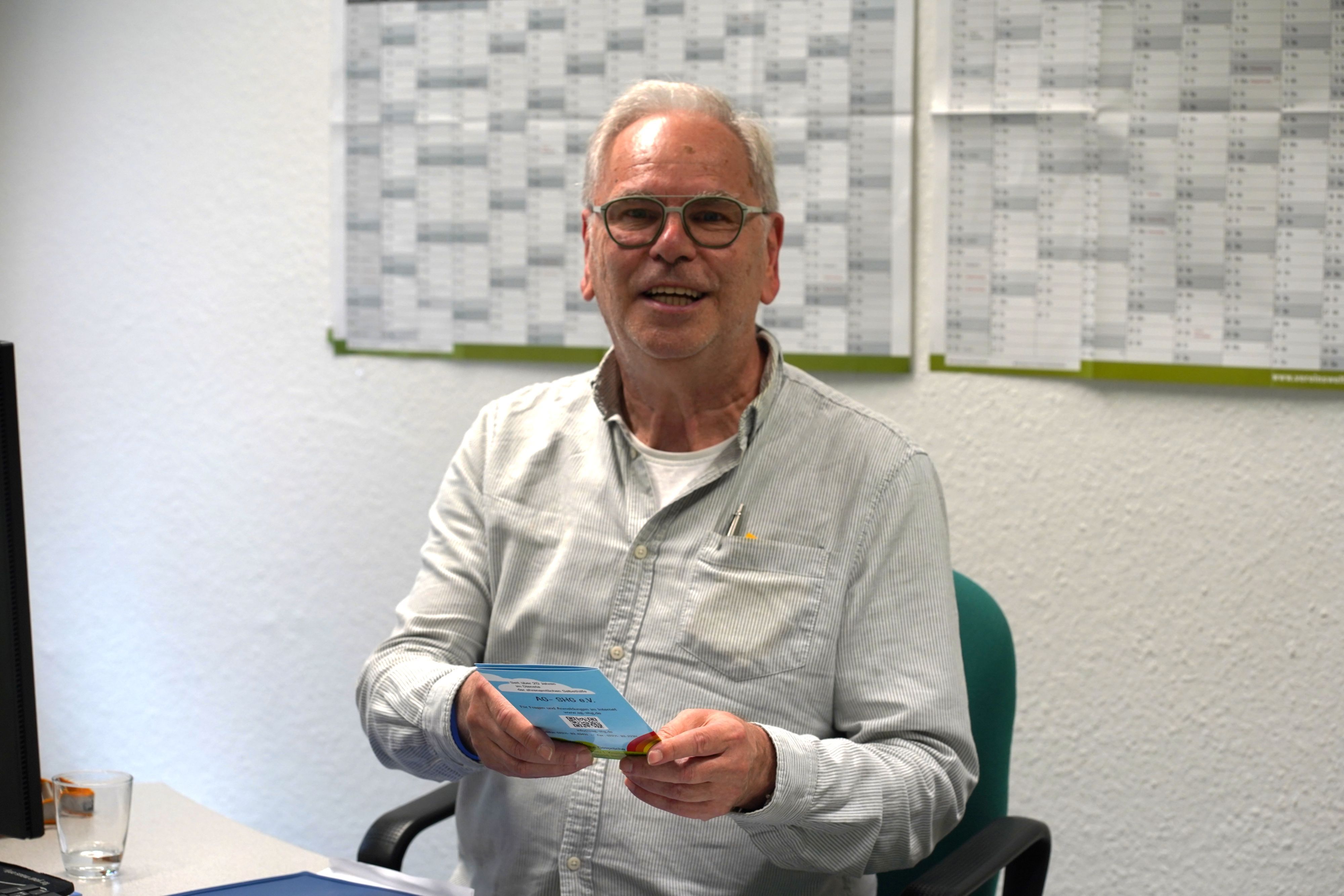 Das Foto zeigt einen Mann mit einer Broschüre in der Hand.