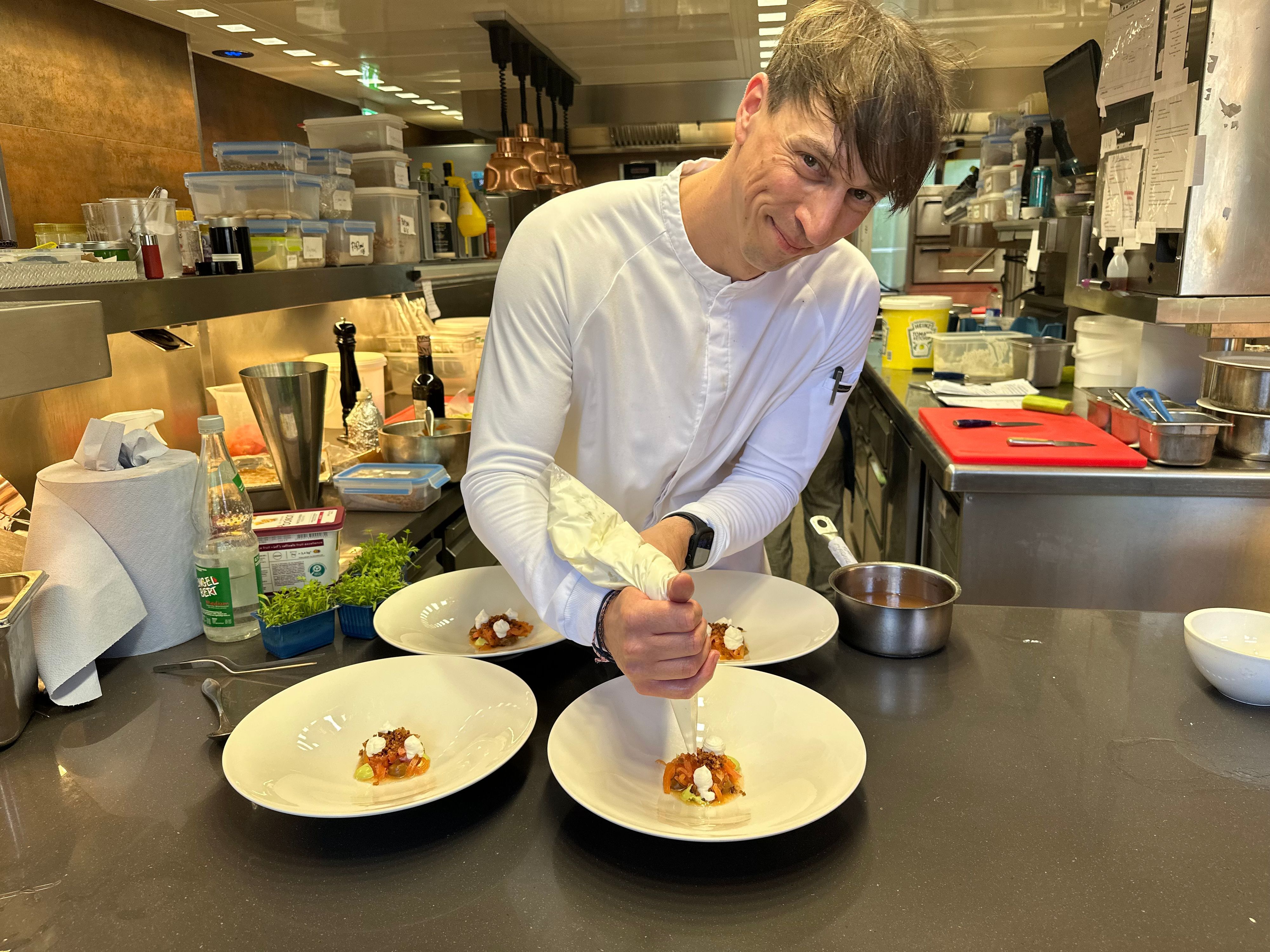 André Siebertz setzt als Patissier kulinarische Akzente. Hier bereit er den Ziegenkäse mit Tomate, Melone, Sauerteig und Liebstöckel auf dem Teller zu.