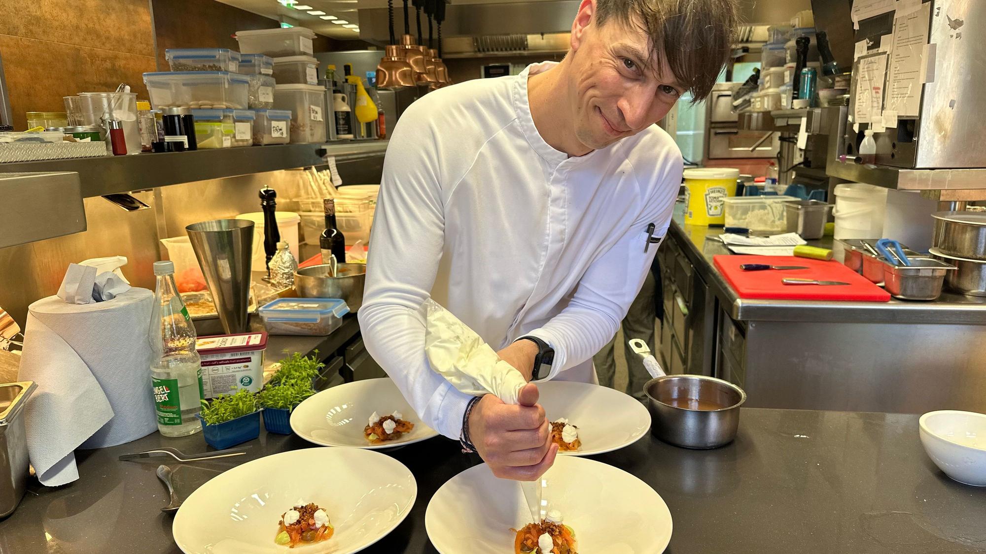 André Siebertz setzt als Patissier kulinarische Akzente. Hier bereit er den Ziegenkäse mit Tomate, Melone, Sauerteig und Liebstöckel auf dem Teller zu.