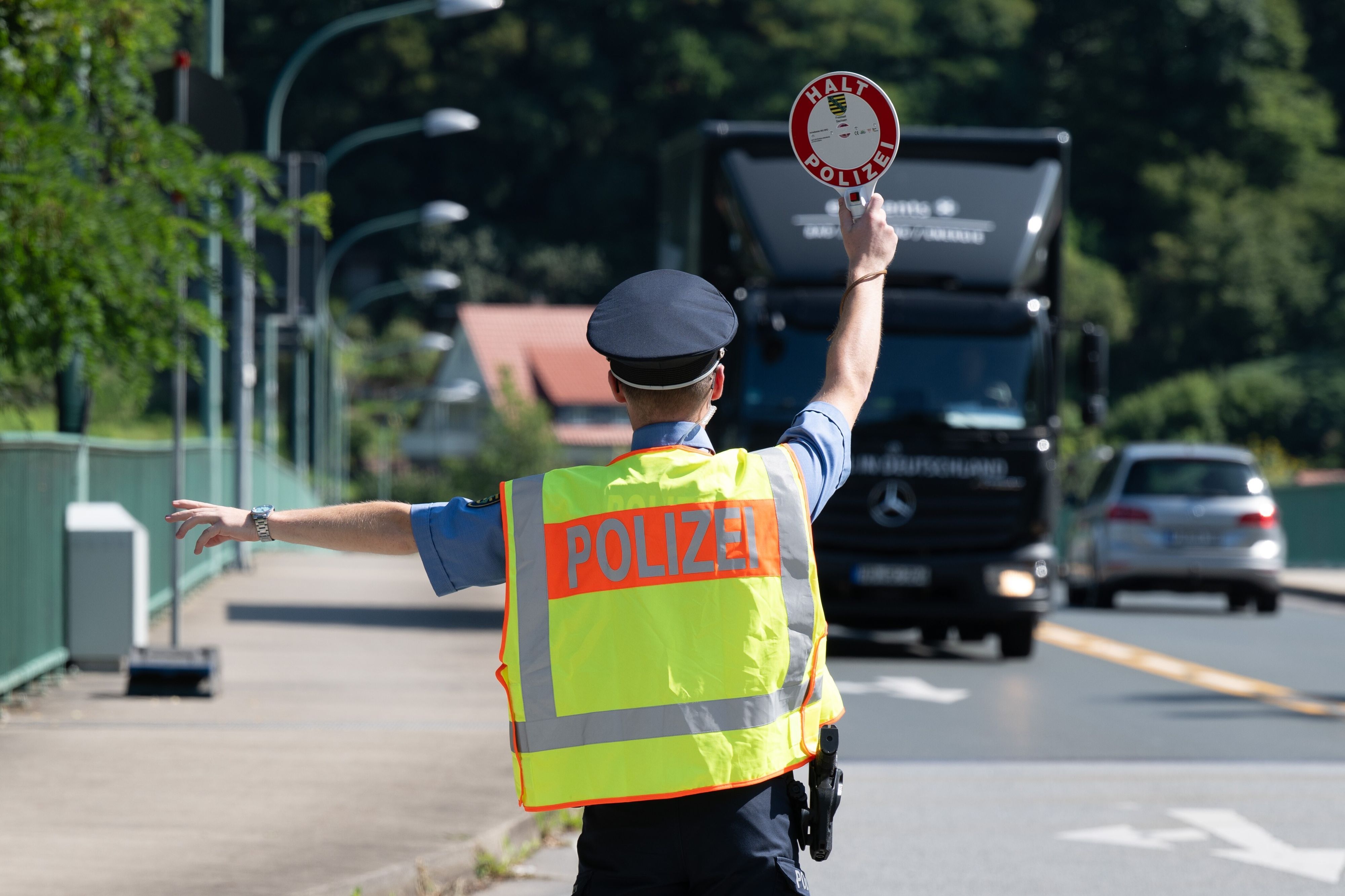 Ein Polizist holt einen Lkw aus dem Verkehr (Symbolfoto).
