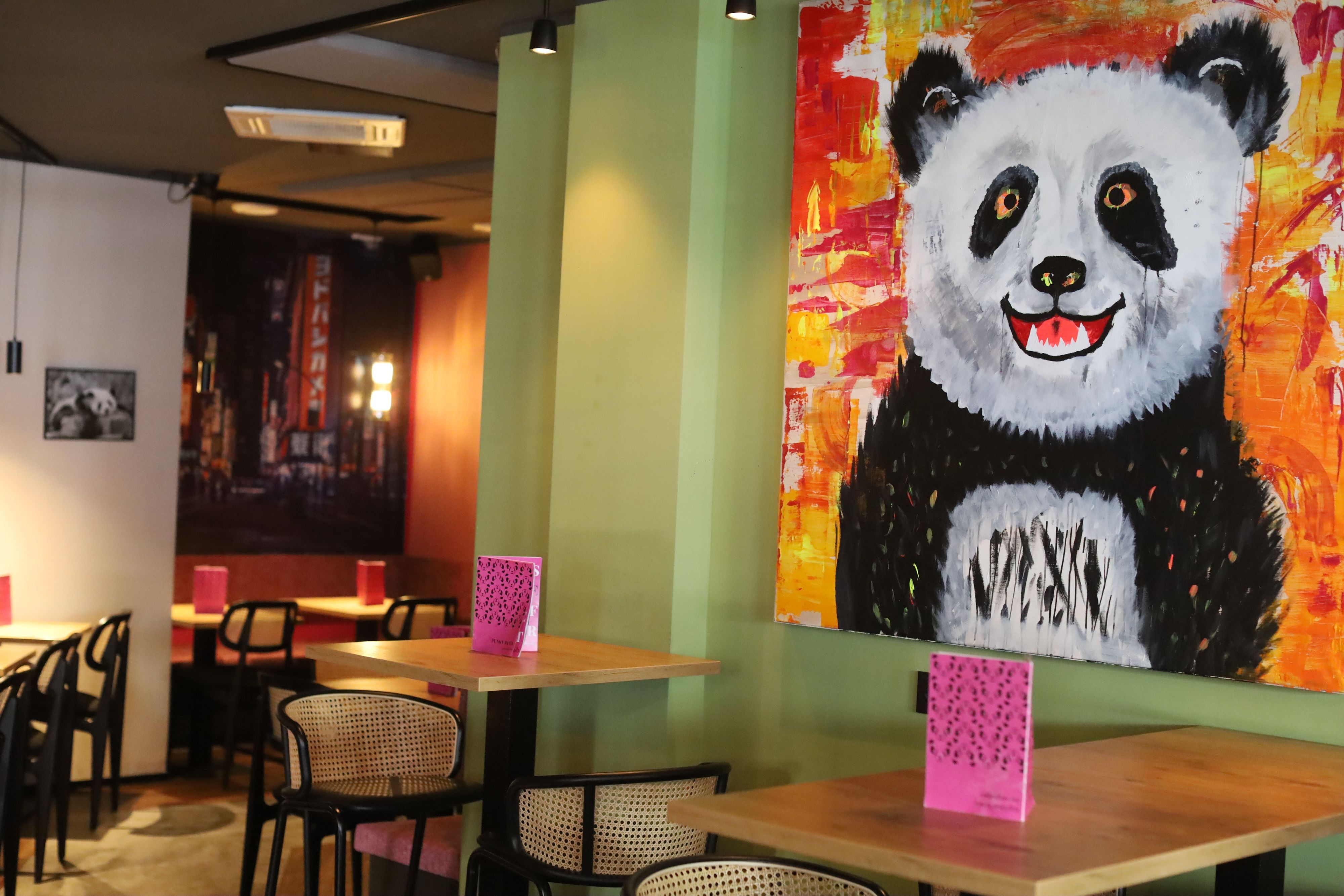 Ansicht des Lokals - an der Wand hängt ein großes Panda-Gemälde.