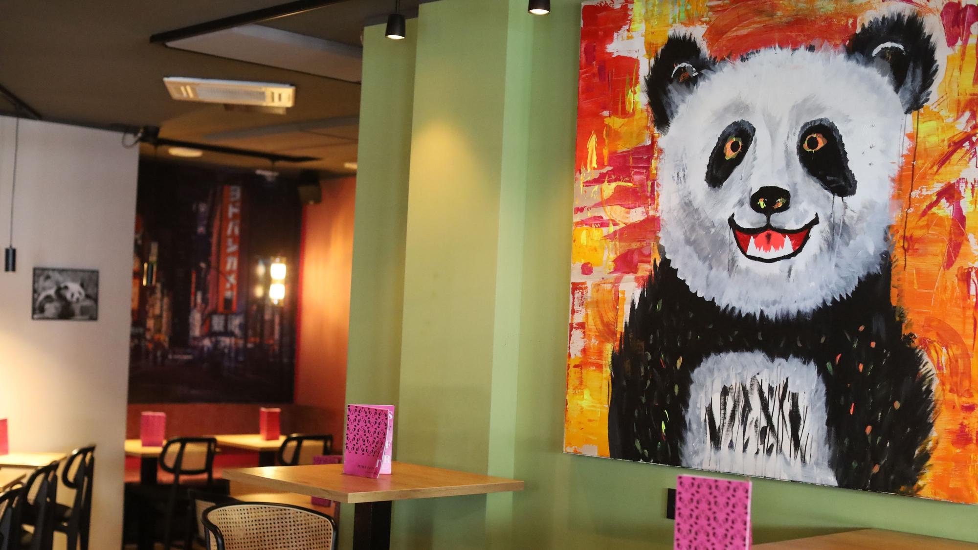 Ansicht des Lokals - an der Wand hängt ein großes Panda-Gemälde.