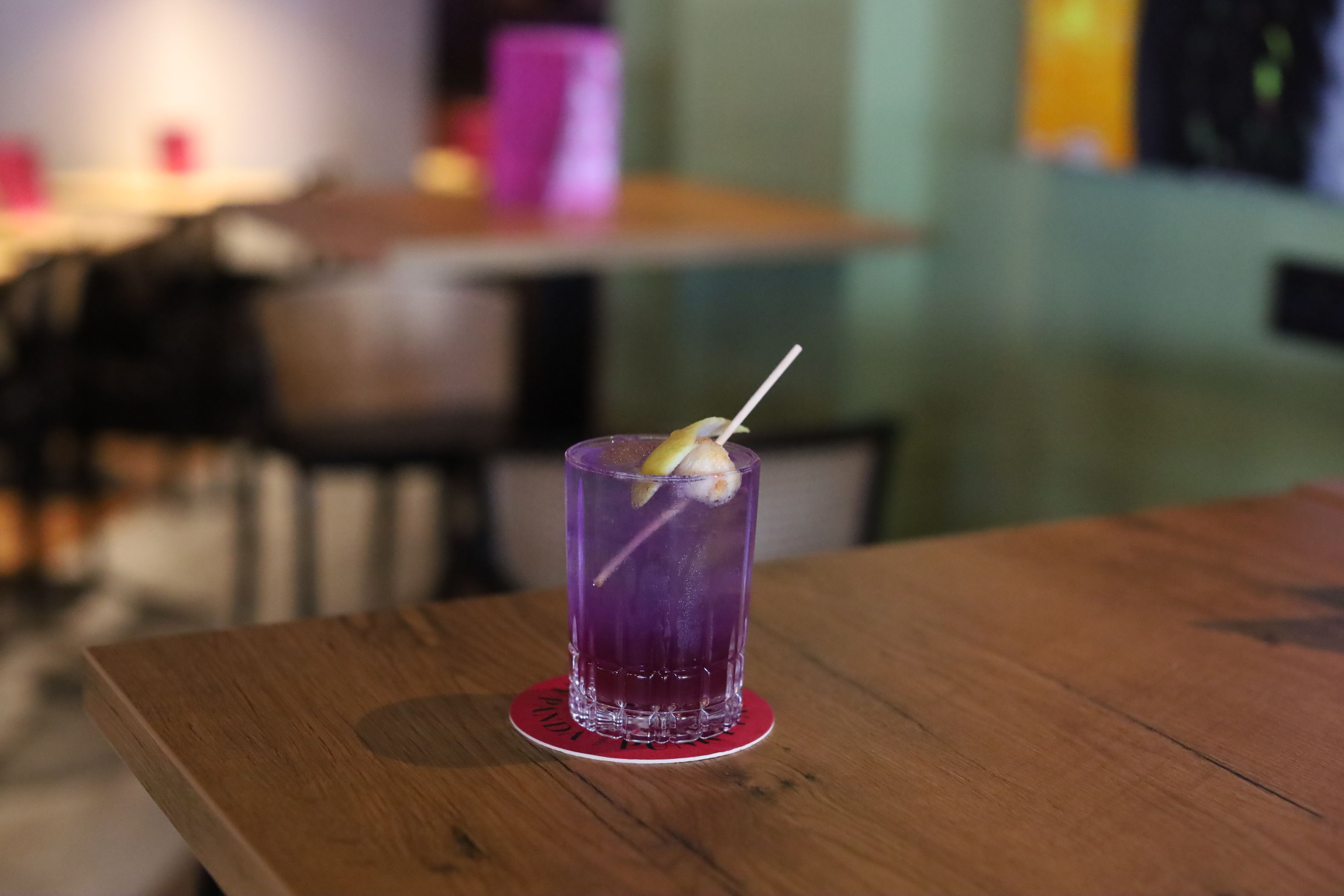 Ein Cocktail in lila Glas steht auf einem Tisch.