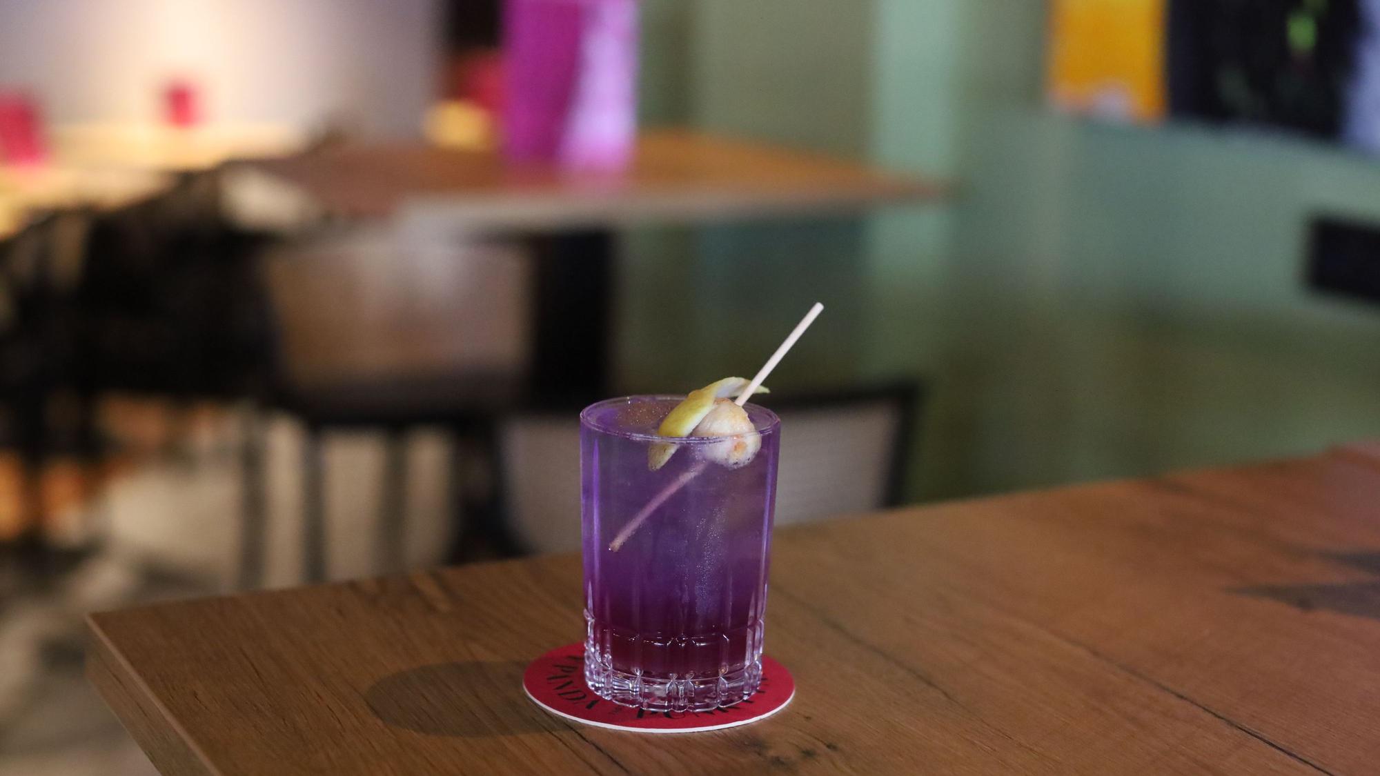 Ein Cocktail in lila Glas steht auf einem Tisch.