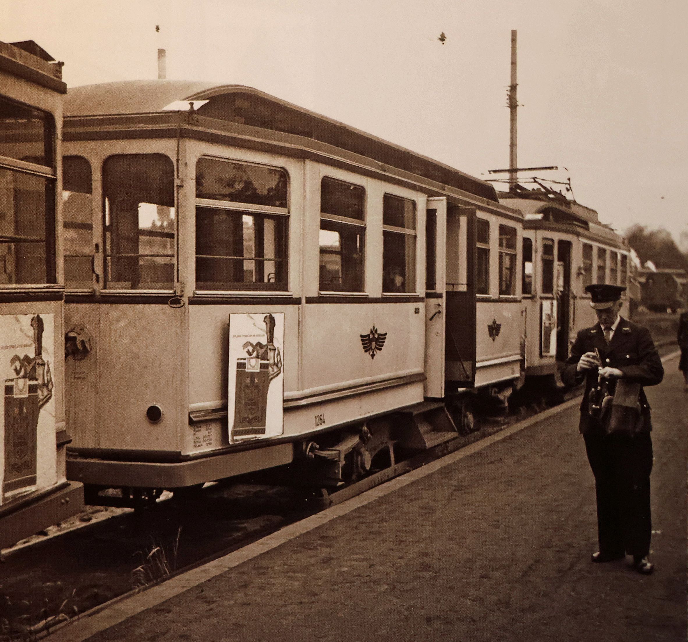Das alte Foto zeigt einen Mann vor einer Bahn.