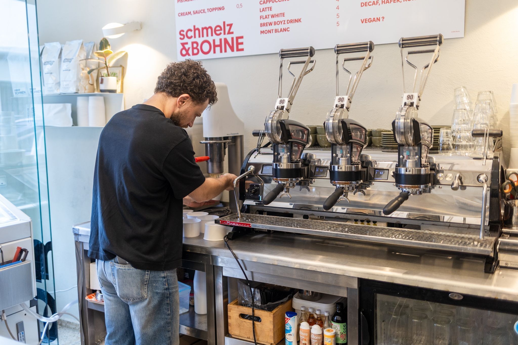 Ein Mann steht vor eine Kaffeemaschine.