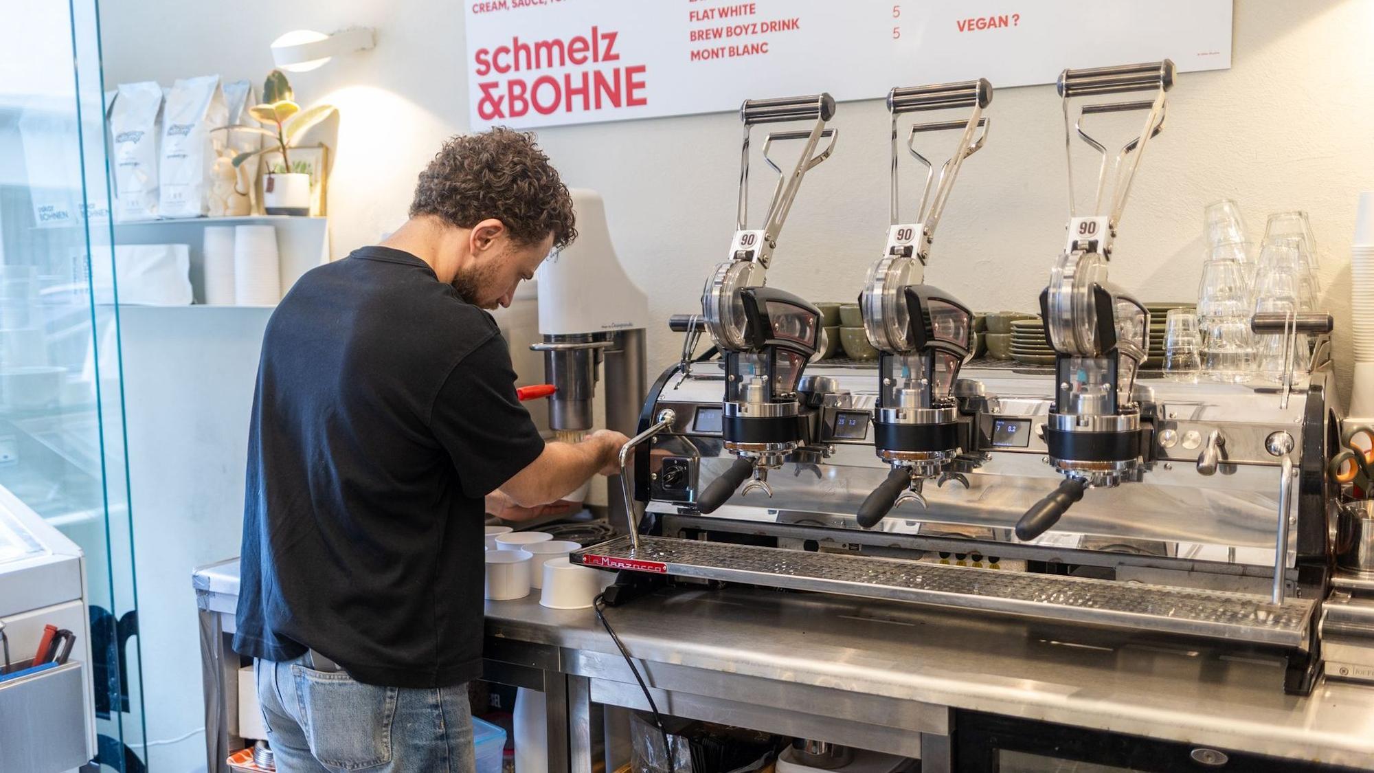 Ein Mann steht vor eine Kaffeemaschine.