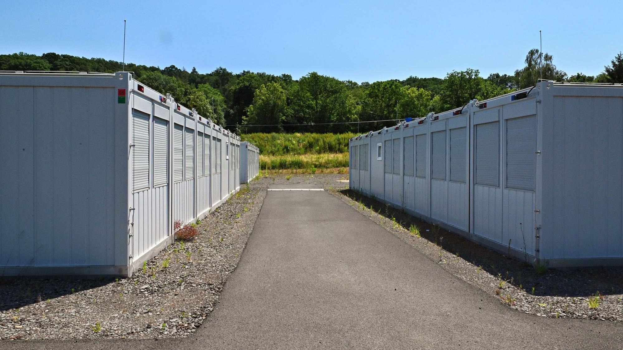 Rechts und links eines asphaltierten Weges stehen Container für Geflüchtete und Obdachlose.