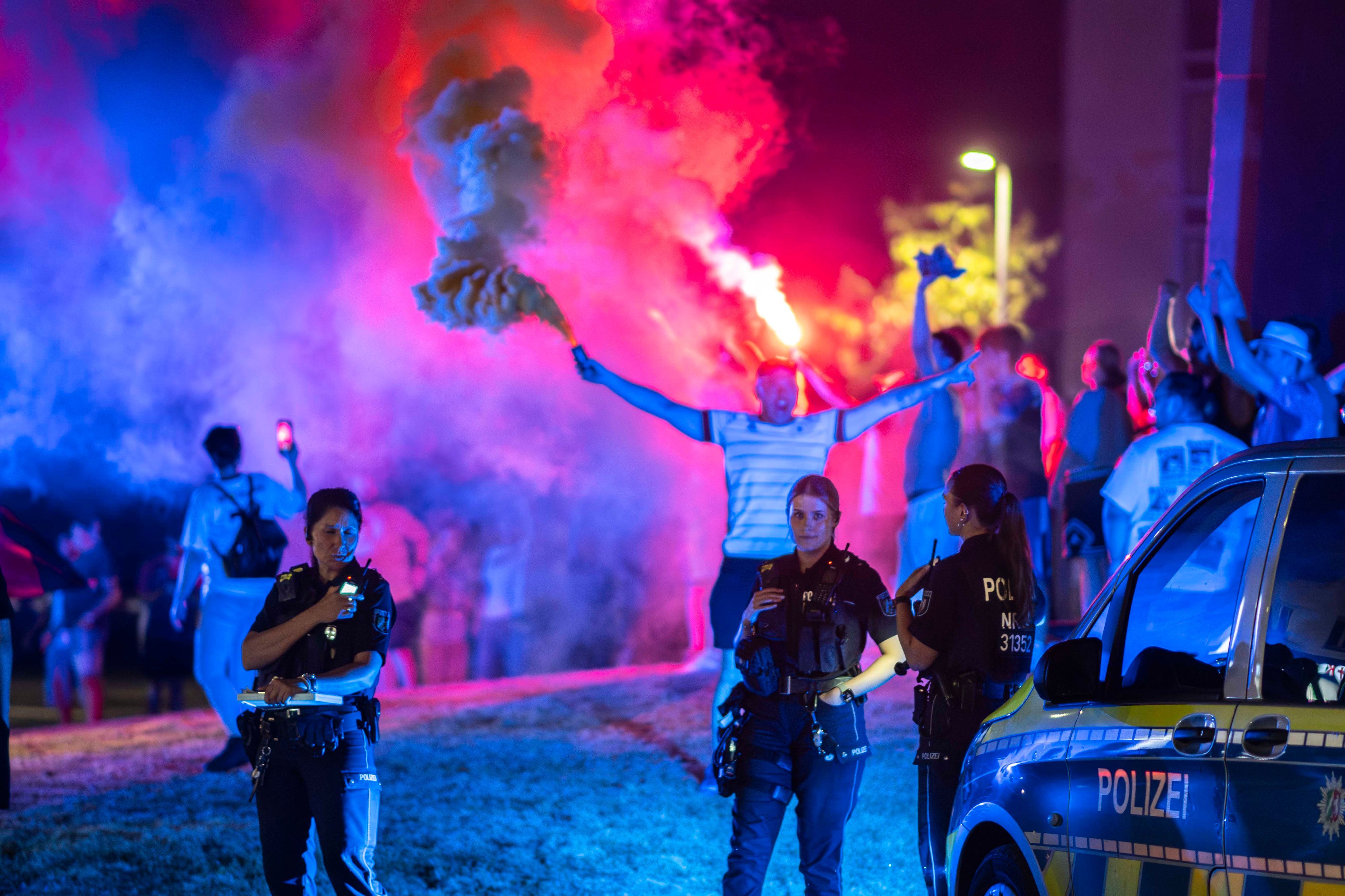 Drei Polizistinnen verfolgen das farbenfrohe Treiben im Europa-Kreisel. Ein Mann hat im Hintergrund eine Rauchfackel gezündet.