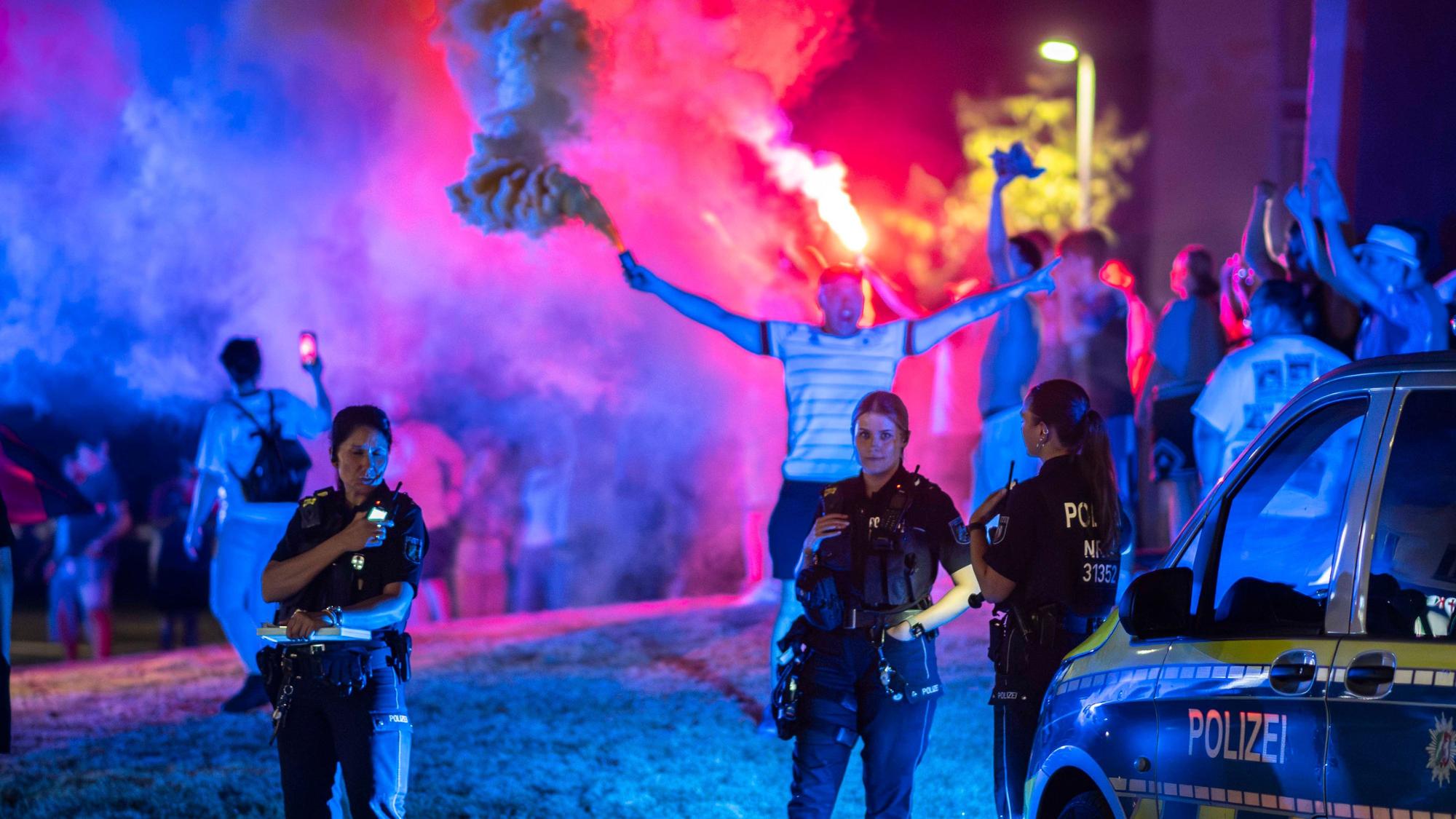 Drei Polizistinnen verfolgen das farbenfrohe Treiben im Europa-Kreisel. Ein Mann hat im Hintergrund eine Rauchfackel gezündet.