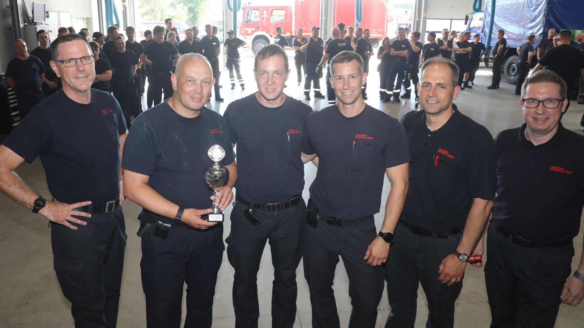 Die Sieger halten ihren Wanderpokal und schauen mit Feuerwehrchef Jörg Köhler und seinen Stellvertretern Frank Haag und Benjamin Severin-von Polheim in die Kamera.