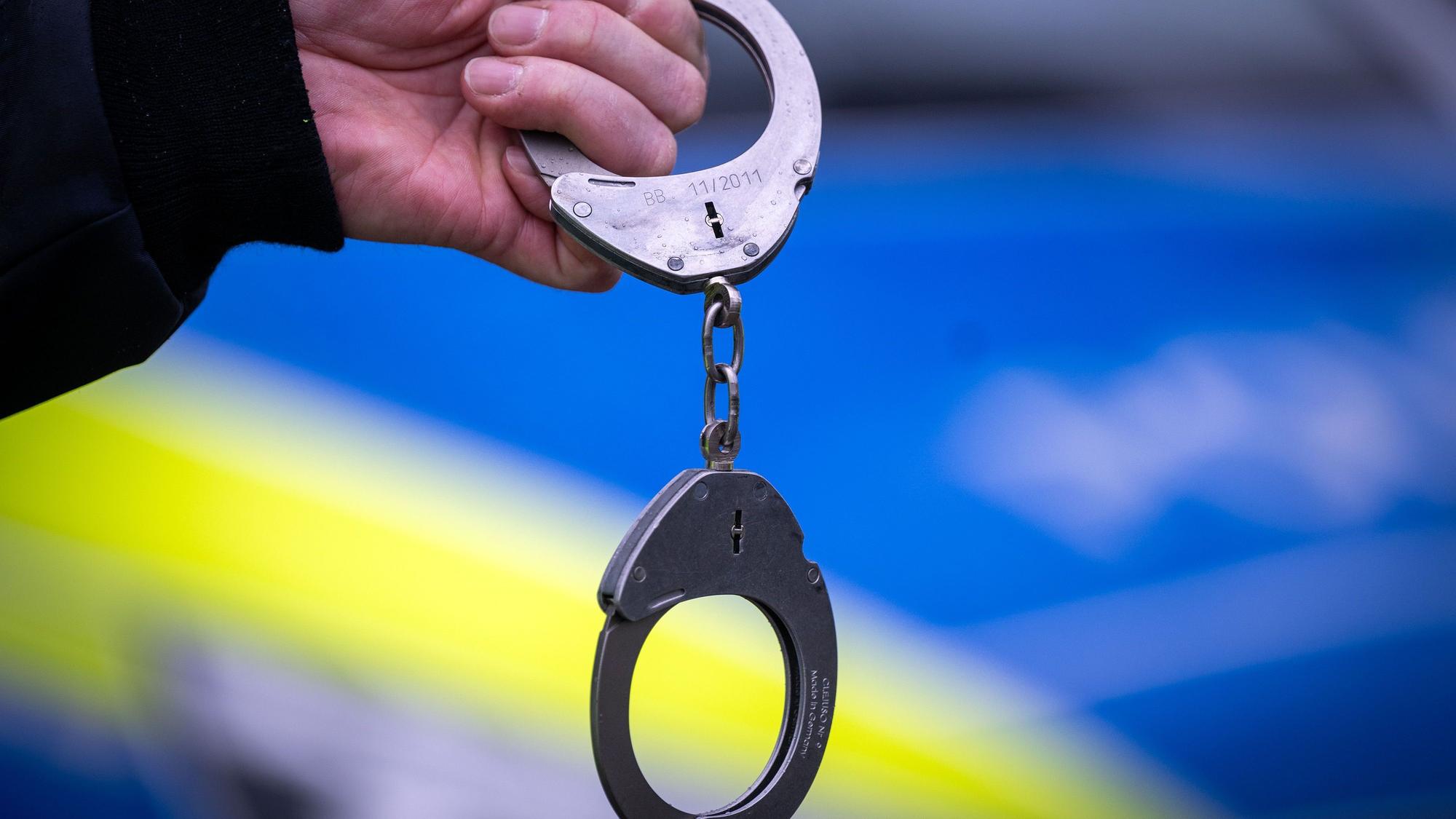 Ein Polizist hält ein Paar Handschellen.