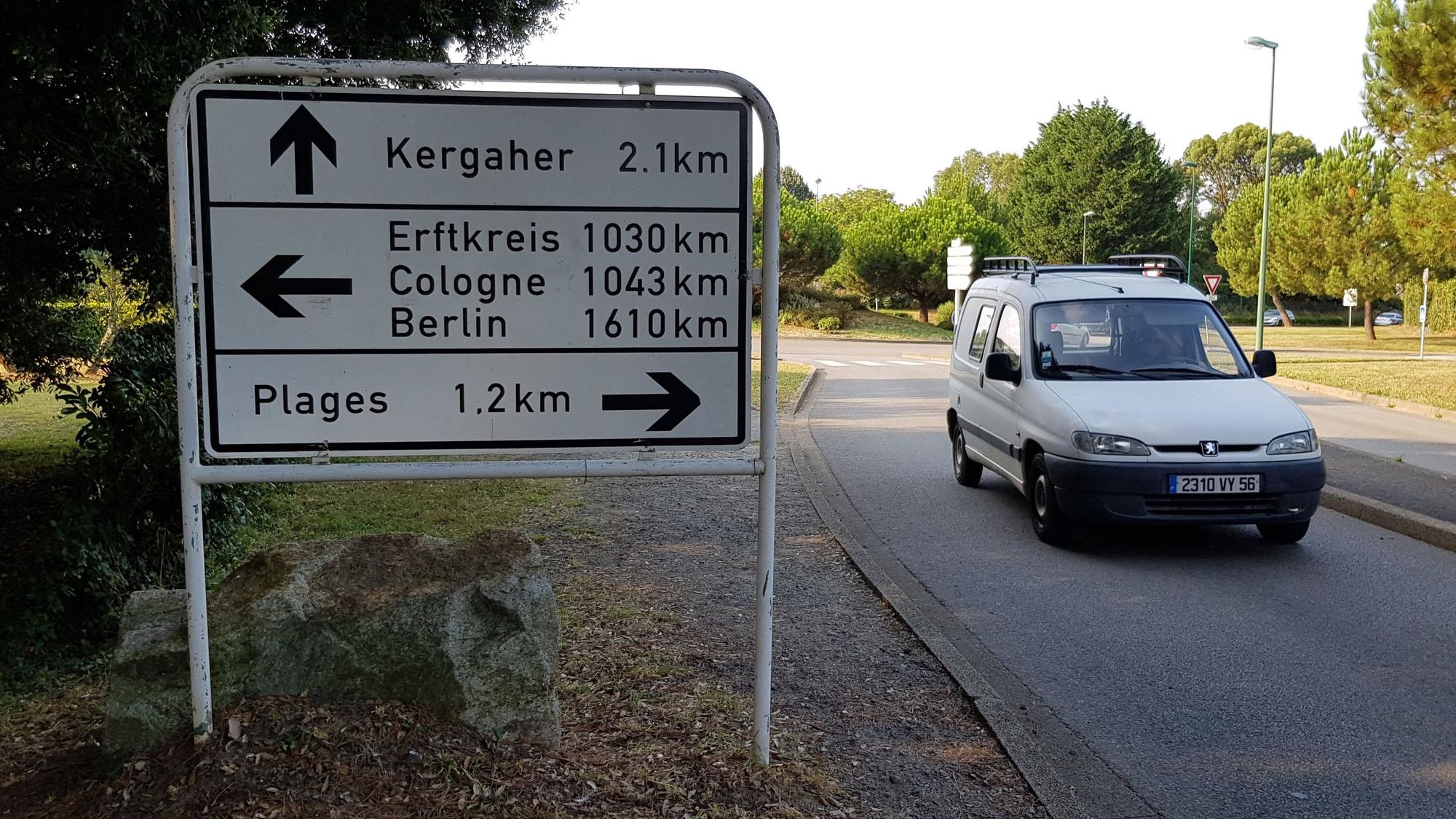 Zu sehen ist ein Verkehrsschild in Frankreich, das die Distanz nach Köln, Berlin und zum Rhein-Erft-Kreis anzeigt.