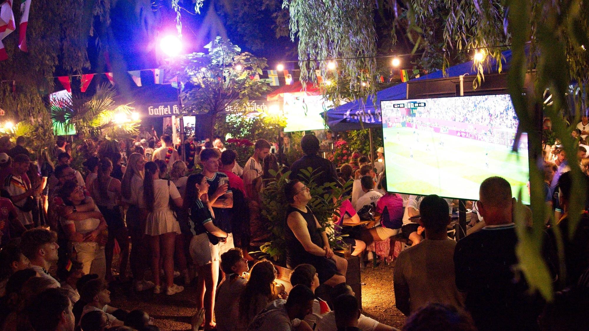 Fans schauen das Spiel gegen die Elfenbeinküste im Biergarten am Aachener Weiher.