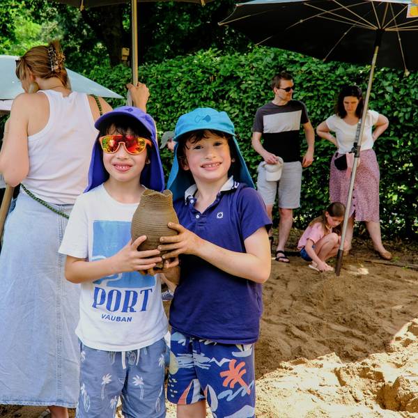 Zwei Kinder halten ein Gefäß in den Händen.