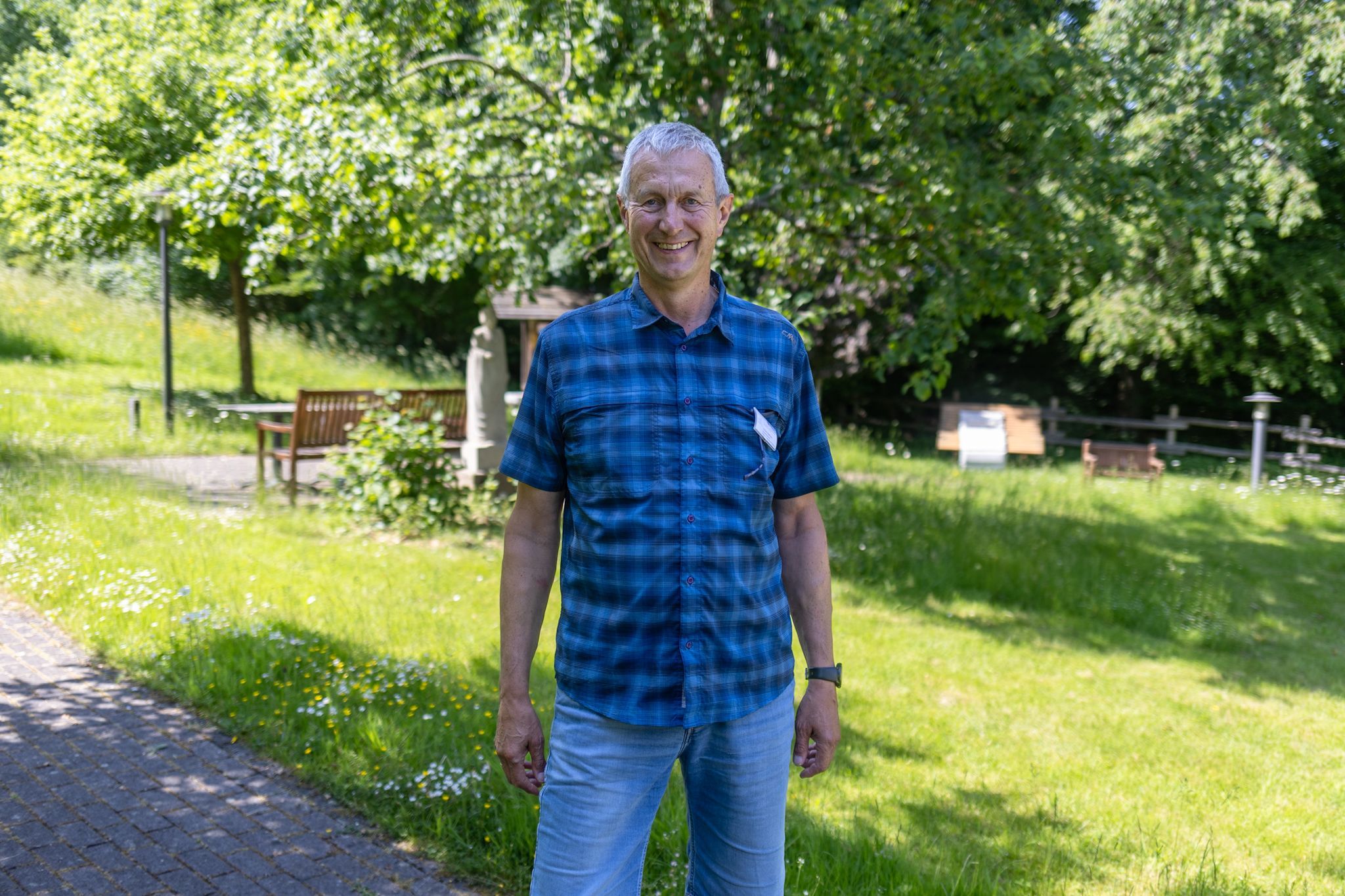 Ein Mann im karierten Hemd steht in einem Garten.