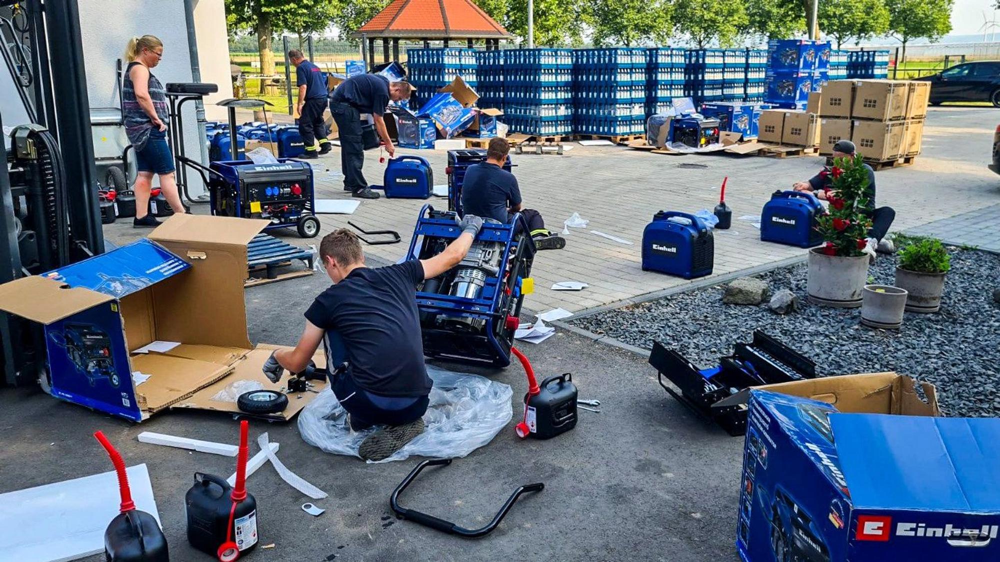 Das Bild zeigt einige Menschen, die Notstromaggregaten zusammenbauen.