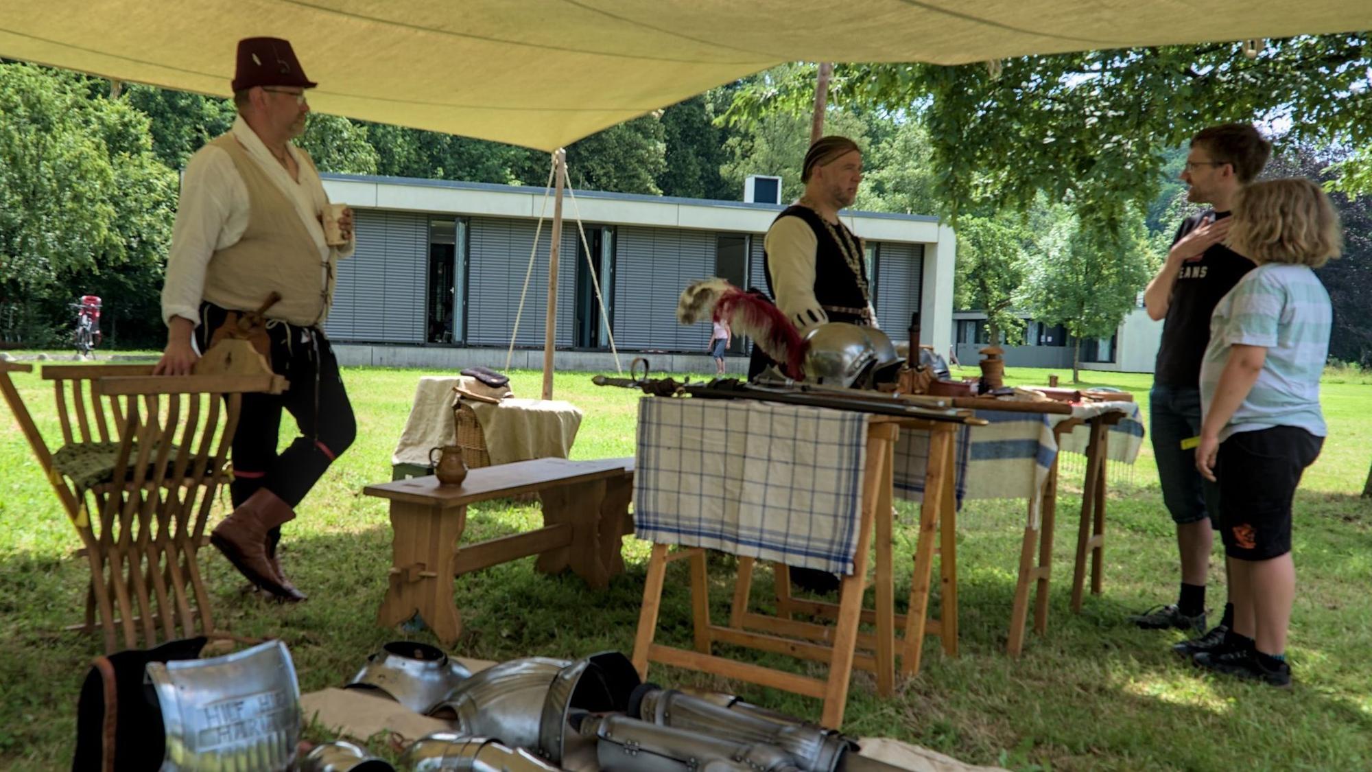 Unter einer Plane steht ein Mann an einem Stand mit kleinen Feuerwaffen.