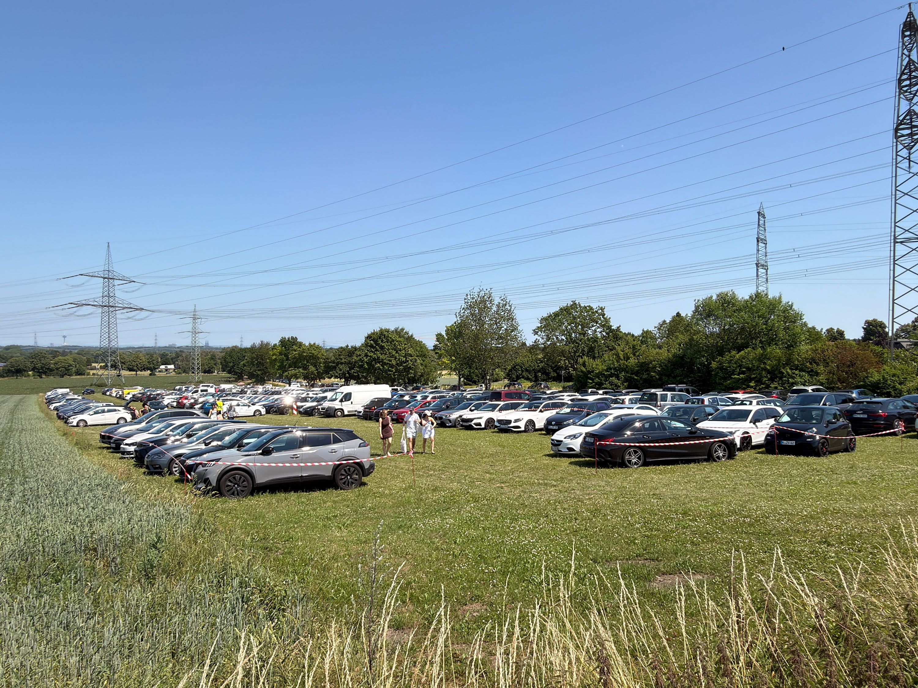 Auf dem Bild ist ein voller Parkplatz auf einer Wiese zu sehen.