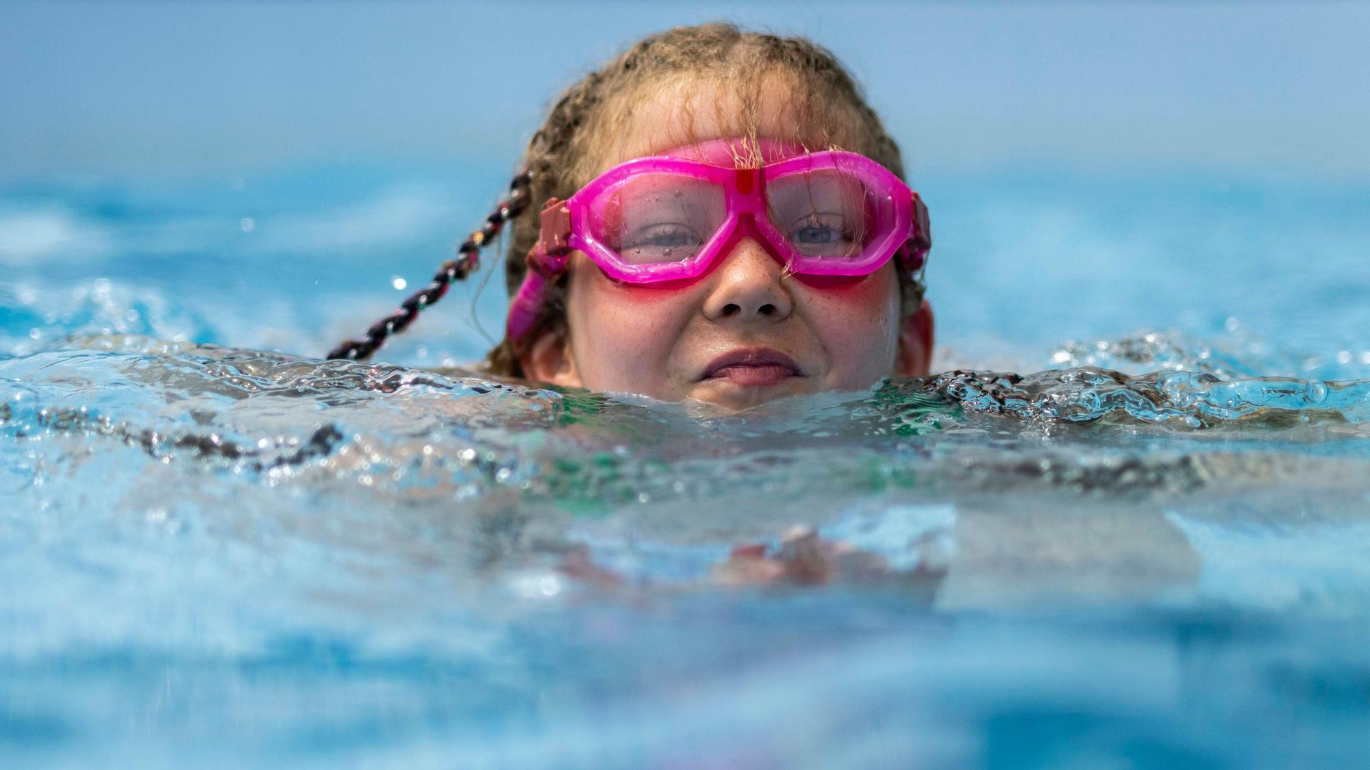 Ein Kind mit rosa Brille schwimmt im Wasser.