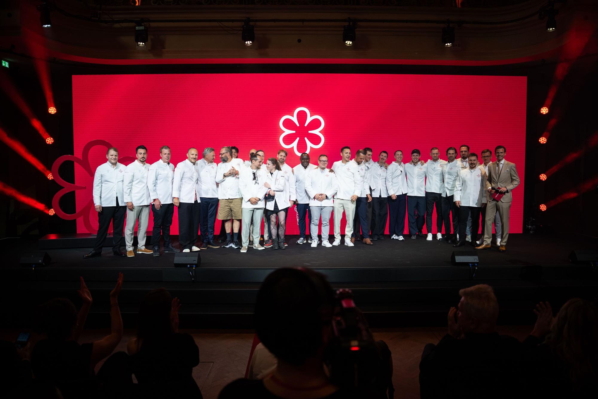 Alle ausgezeichneten 1-Sterne-Köche und Restaurateure stehen für ein Gruppenfoto auf der Bühne.