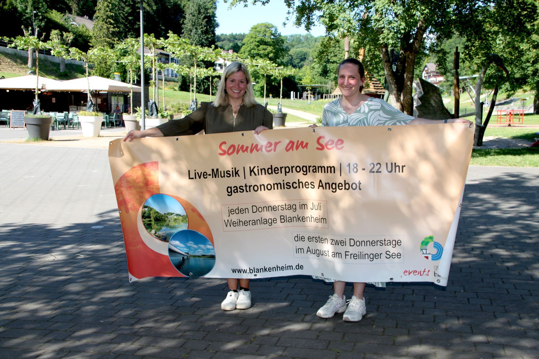 Bürgermeisterin Jennifer Meuren und Touristikerin Janina Bresgen (v.l.) halten ein Veranstaltungsbanner.
