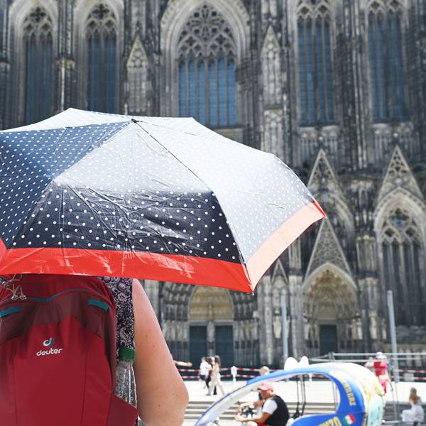 Eine Person schützt sich mit einem Schirm vor der Sonne.