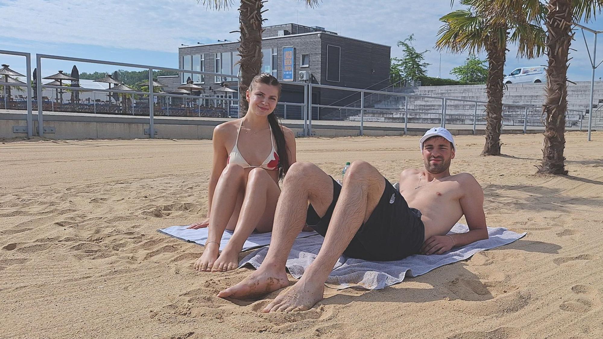 Ein Paar liegt am Sandstrand.
