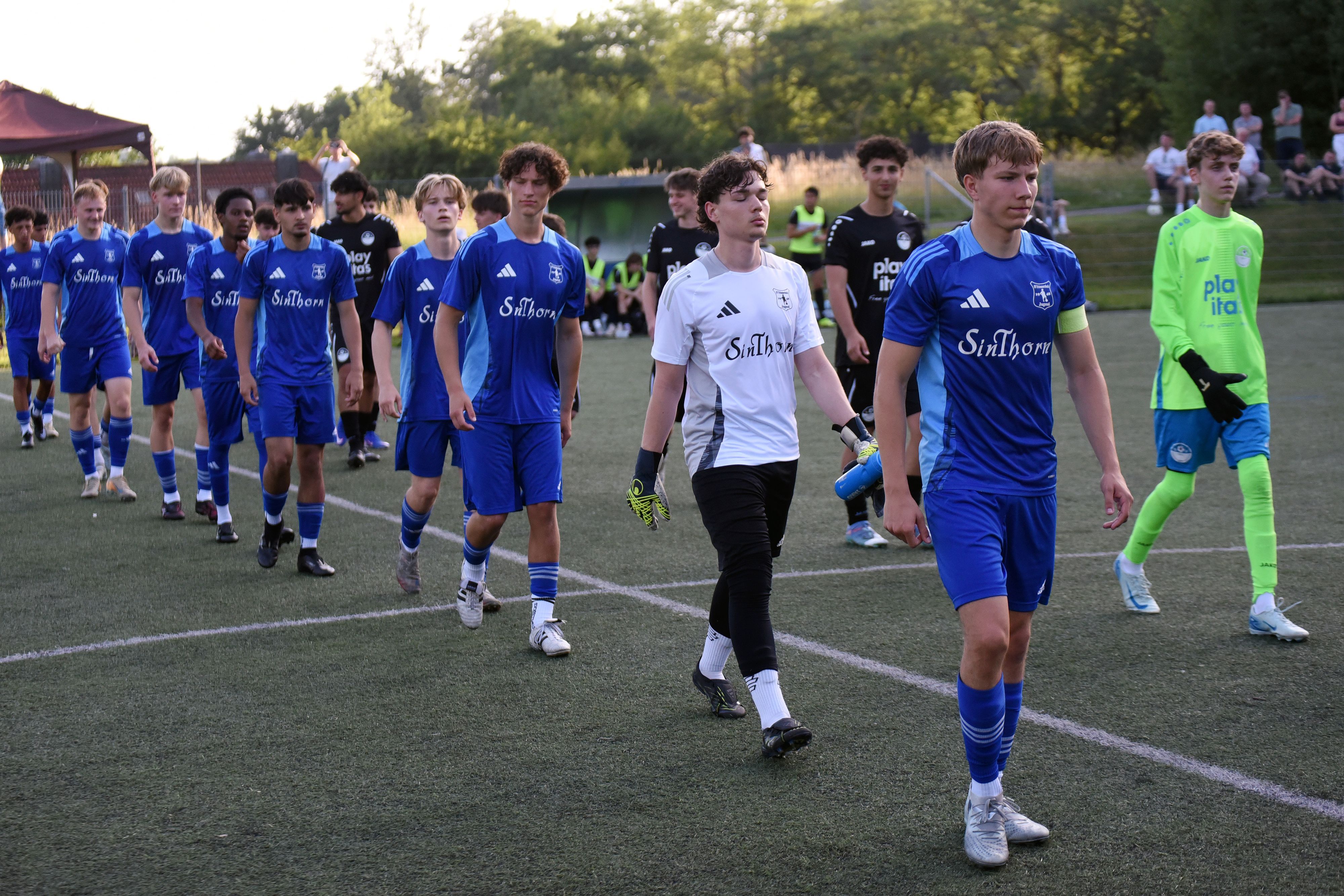 Zwei Fußballmannschaften betreten das Spielfeld.