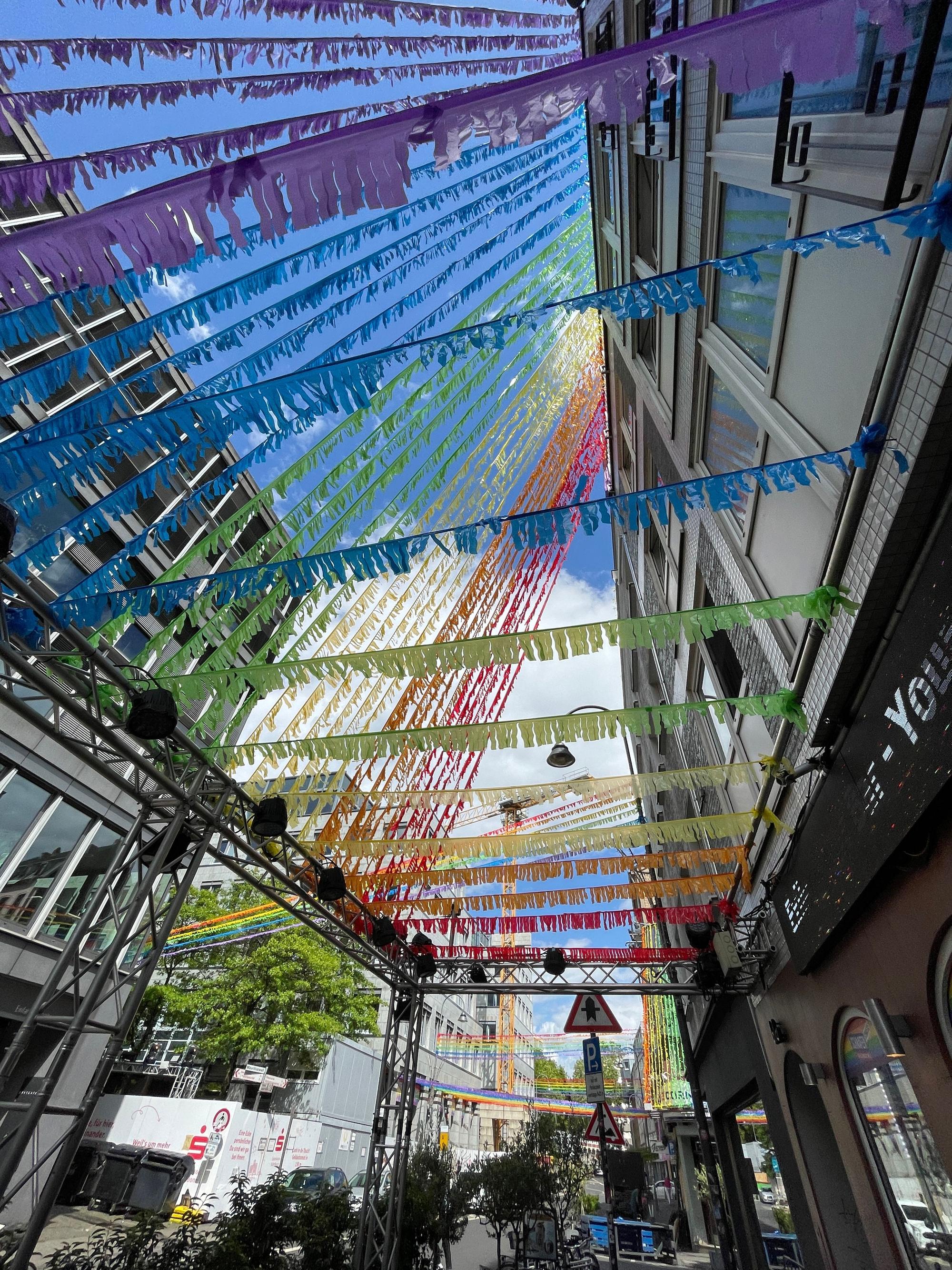 Eine Straße ist mit Girlanden in Regenbogenfarben dekoriert.