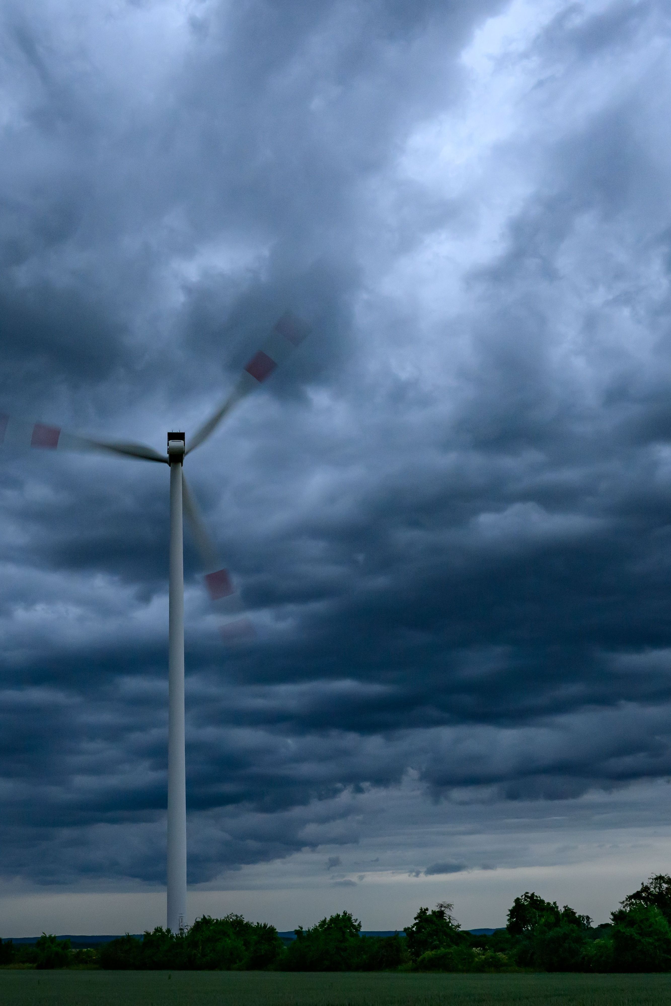 Dunkle Gewitterwolken ziehen am späten Abend über einen Windenergiepark. (Symbolbild)