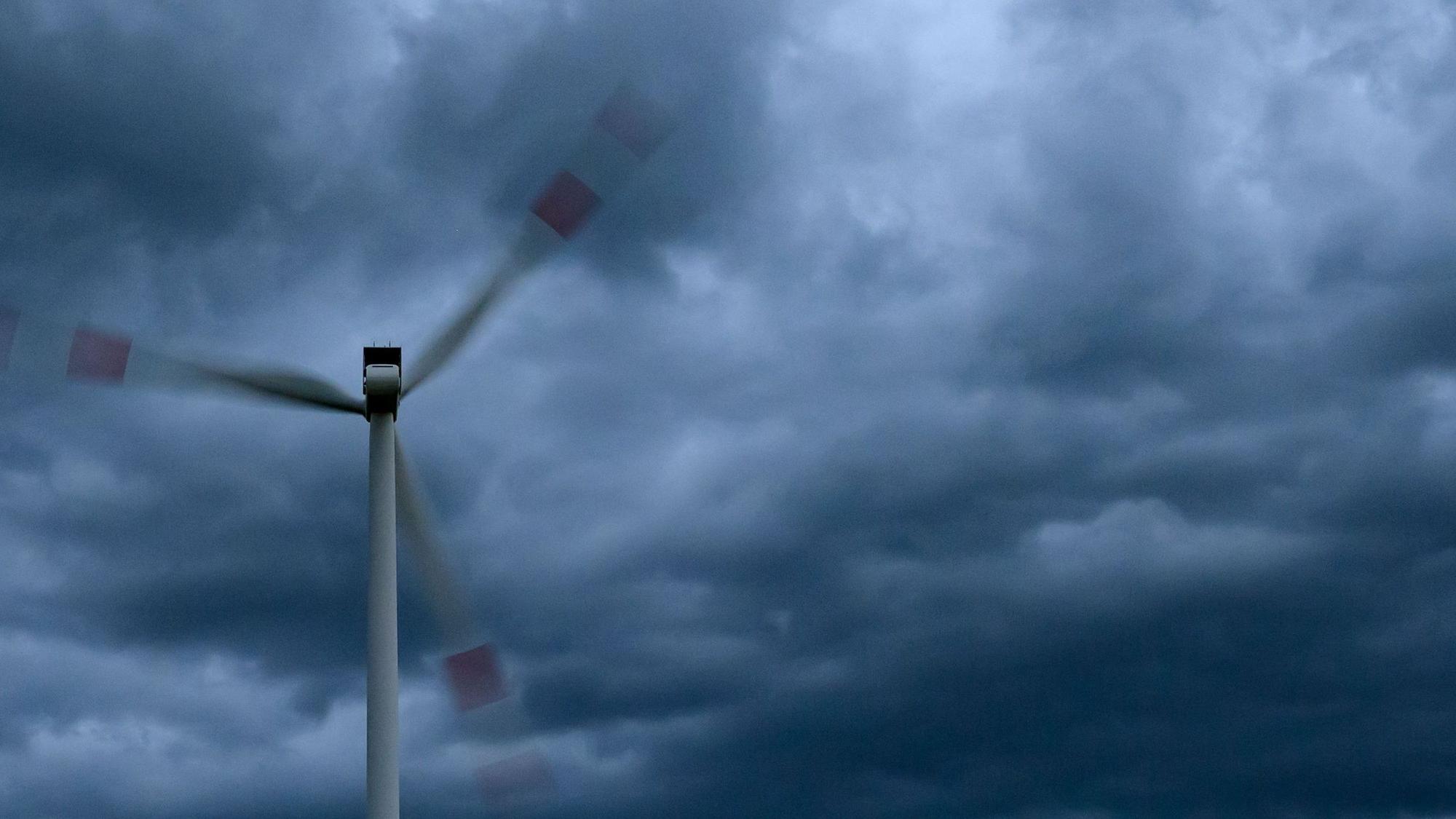 Dunkle Gewitterwolken ziehen am späten Abend über einen Windenergiepark. (Symbolbild)