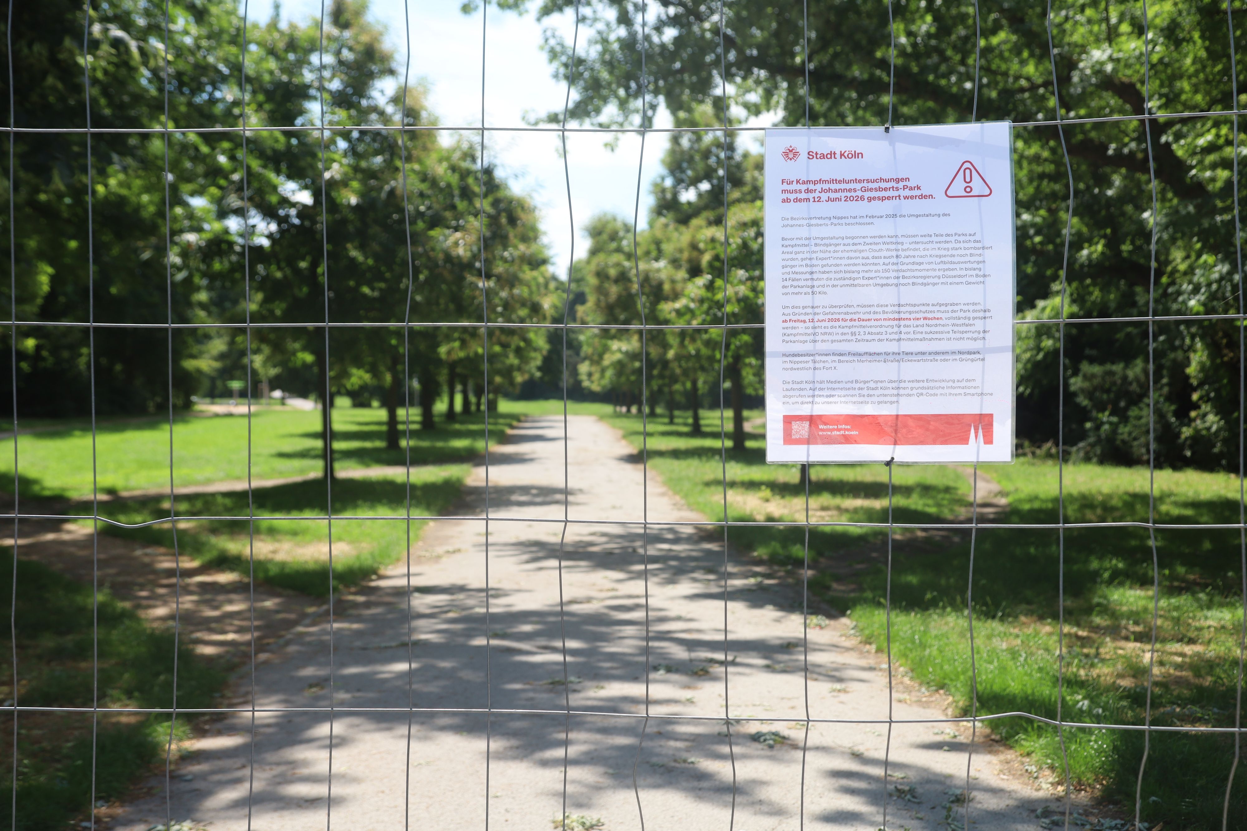 23.06.2026, Köln: Ein Schild der Stadt Köln informiert an einem Bauzaun über die Sperrung des Johannes-Giesberts-Parks für Kampfmitteluntersuchungen. Der Park bleibt während der Arbeiten für Besucher geschlossen. Foto: Arton Krasniqi